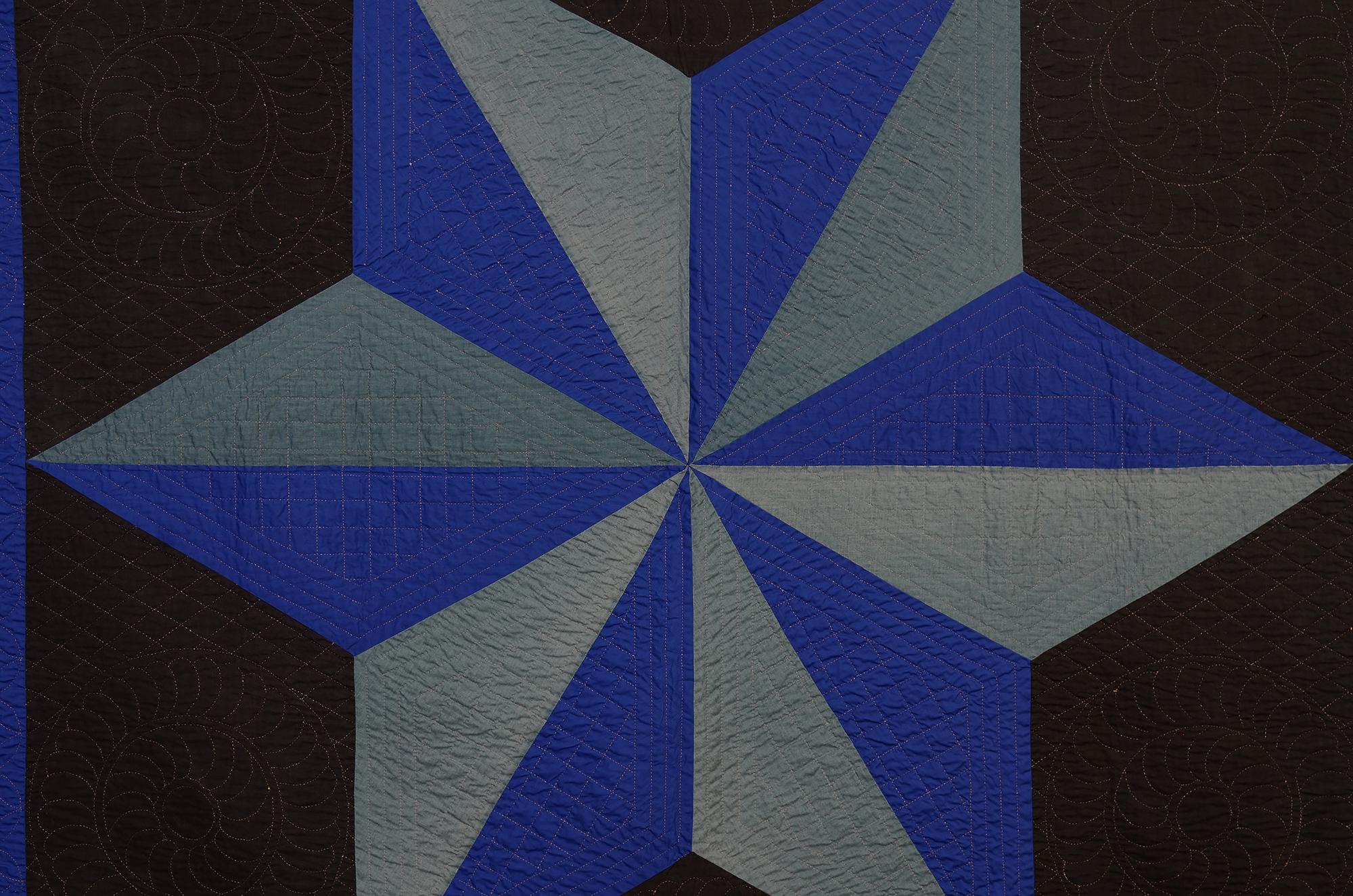 This most unusual Ohio Amish quilt might go by either the name Star of the East or North Star. In either case, the six point star presents a powerful image. It is especially dramatic done on a black ground with two shades of blue creating three