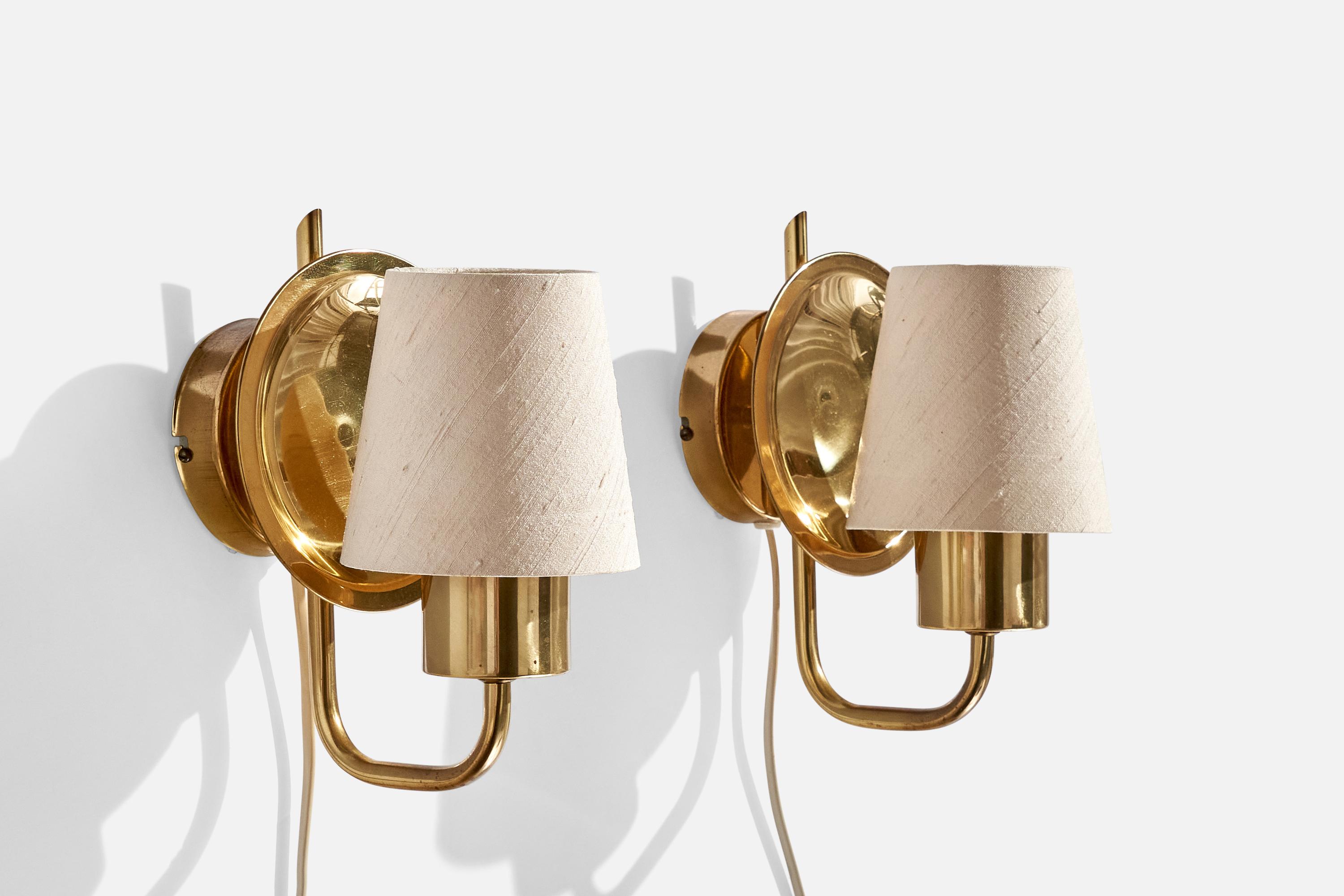 A pair of brass and off-white fabric wall lights produced by ÖIA, Sweden, c. 1970s.

Overall Dimensions (inches):  8” H x  5” W x  6.25“D
Back Plate Dimensions (Inches):  3.25” H x 3.25” W x .875” D
Bulb Specifications: E-14 Bulbs
Number of Sockets