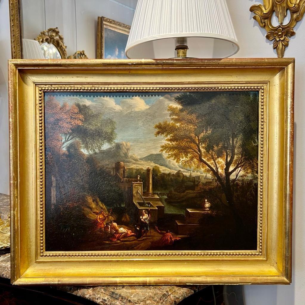 We present you with this wonderful oil painting on canvas mounted on wood, depicting a lively scene with elements such as characters and ruins of ancient times. It offers a striking sense of depth with mountains and a sky in the background. The