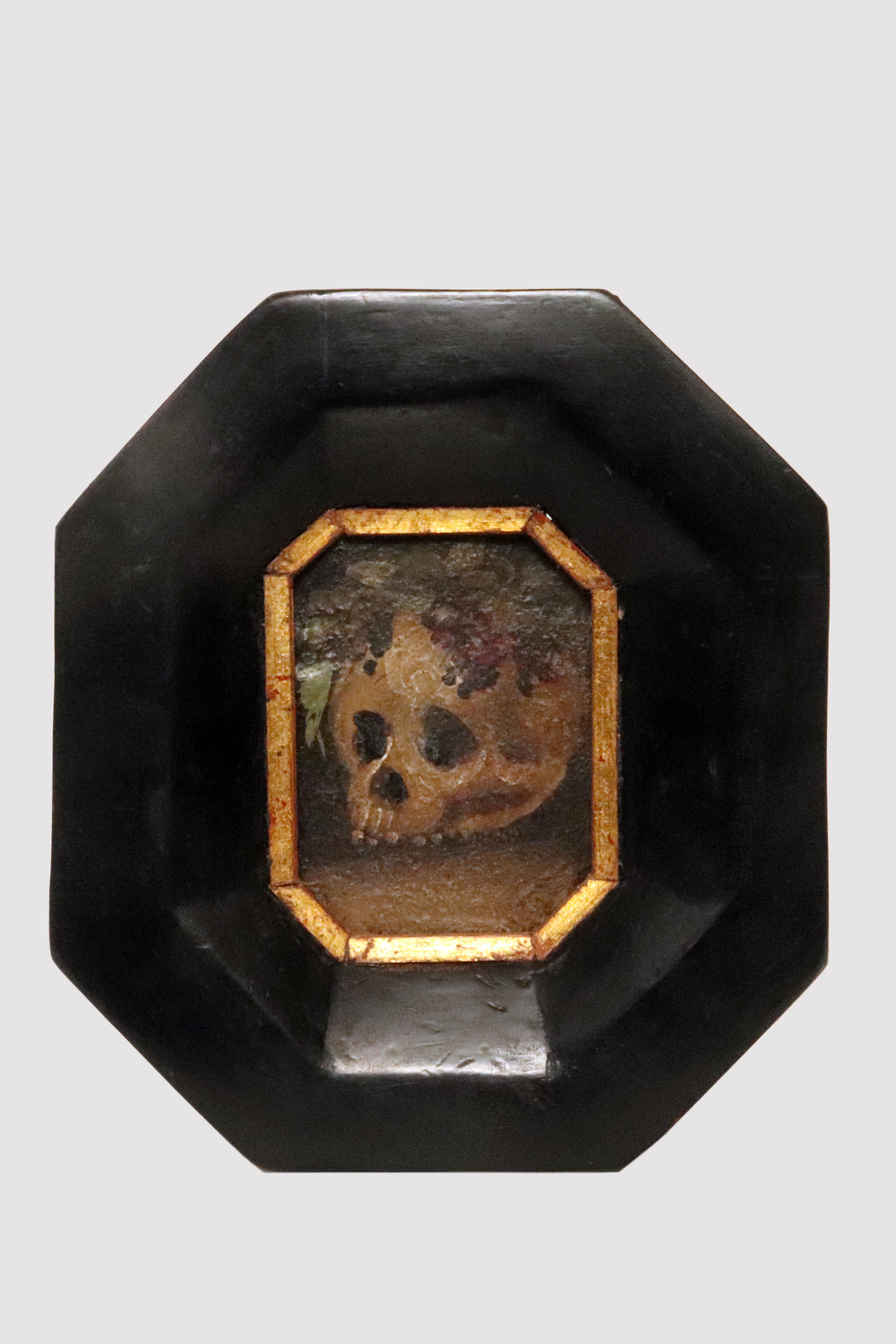 Oil painting on iron plate, depicting a Vanitas with skull and fruit. Octagonal frame in interlocking ebonized wood with flaring to match the painting and gold profiling on lead. Italy late 17th century.