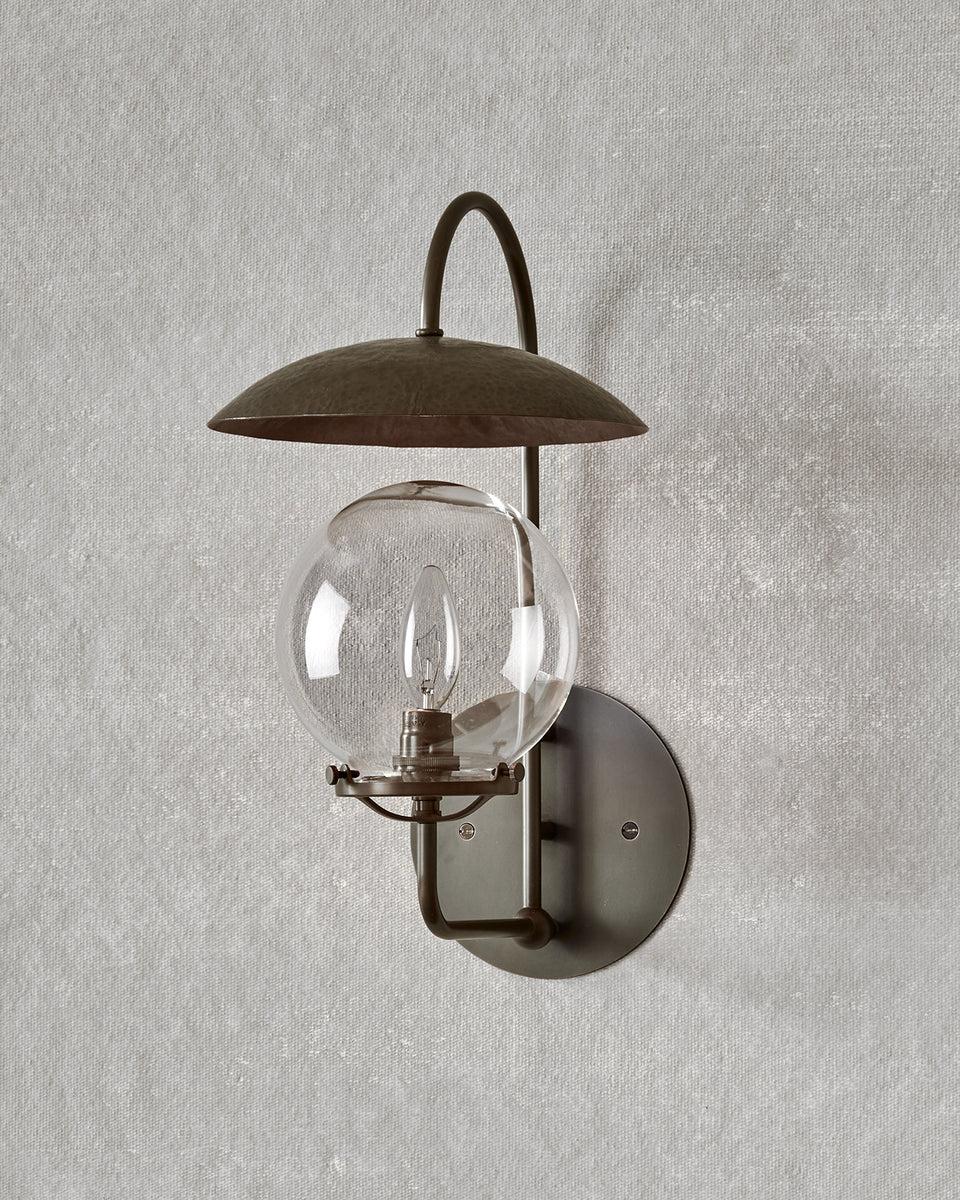 The Mia Sconce is capped with a suspended hand-hammered bronze shade that reflects a warm glow.

OVERALL DIMENSIONS
8.5
