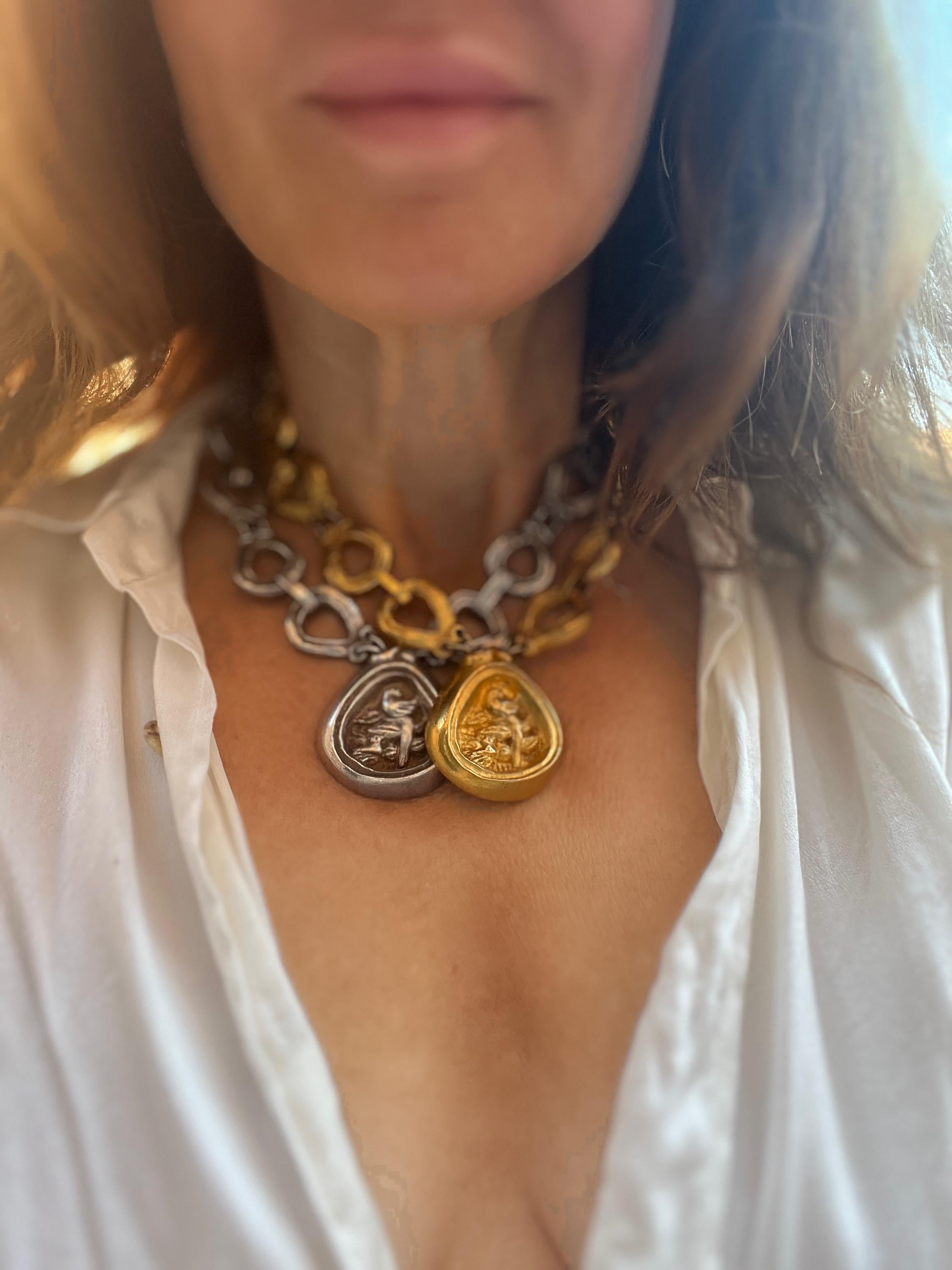 Collana articolata in bronzo argentato con maglie grandi. Medaglione a forma di pera con decorazione a semi-rilievo con uccelli. Firmato sul retro del medaglione. H. H. : 4,5 cm  L : 26 cm   La poesia, l'umorismo e l'ispirazione di Line Vautrin