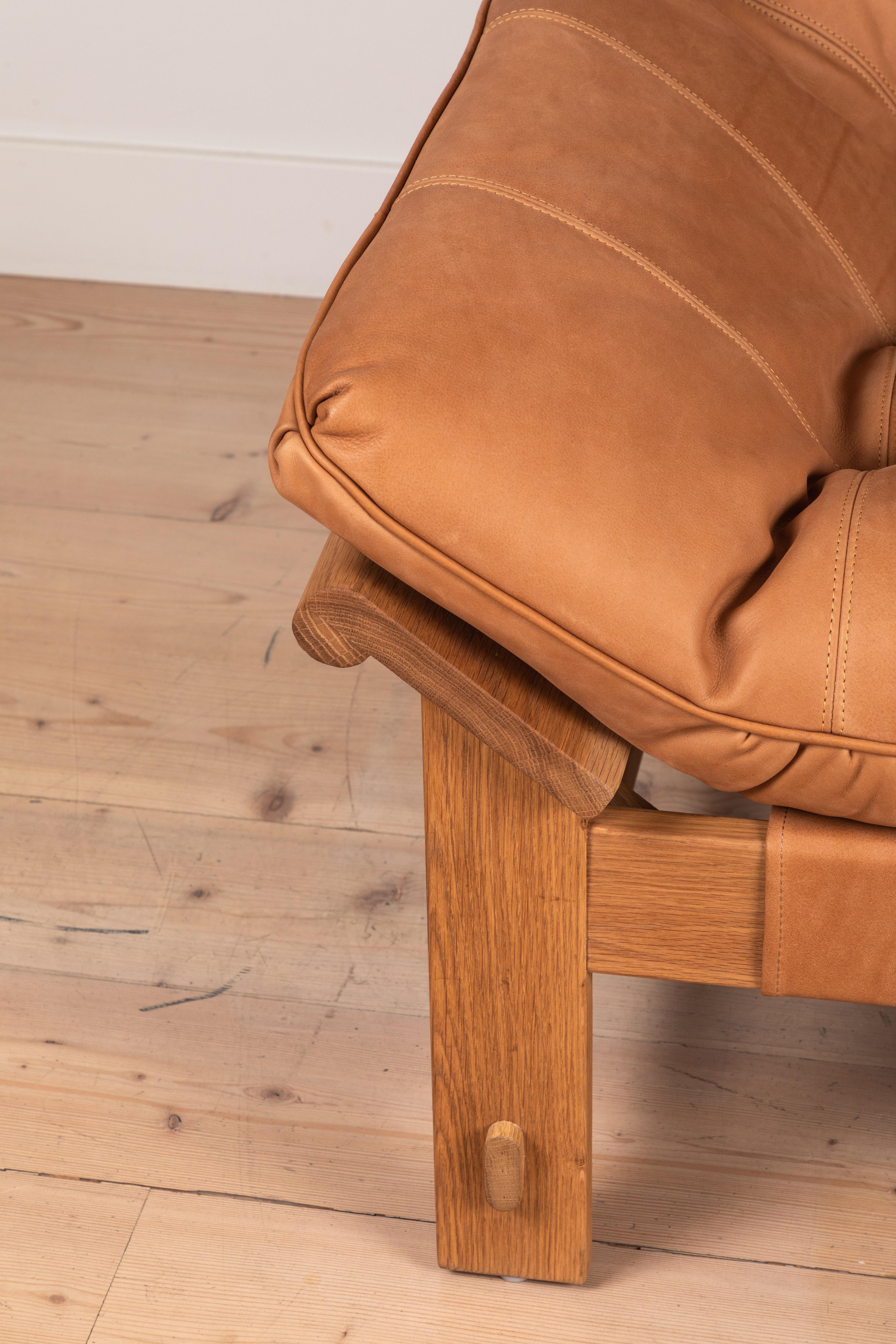 The Ojai lounge chair features a solid white oak or solid walnut base and a single tufted leather cushion with leather straps. Shown here in deer tan leather and oiled oak.
         