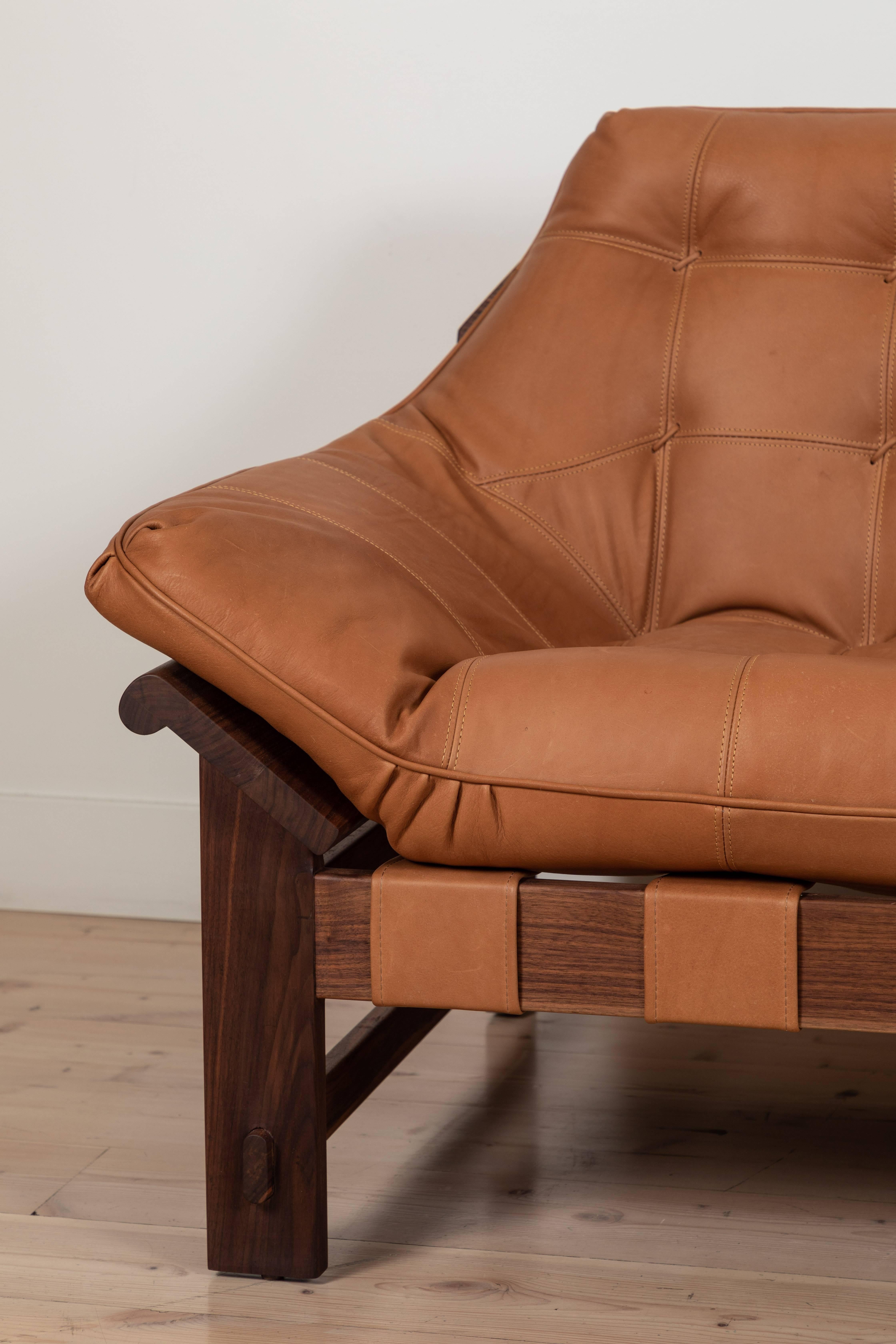 The Ojai sofa features a solid white oak or solid walnut base and a single tufted leather cushion with leather straps.