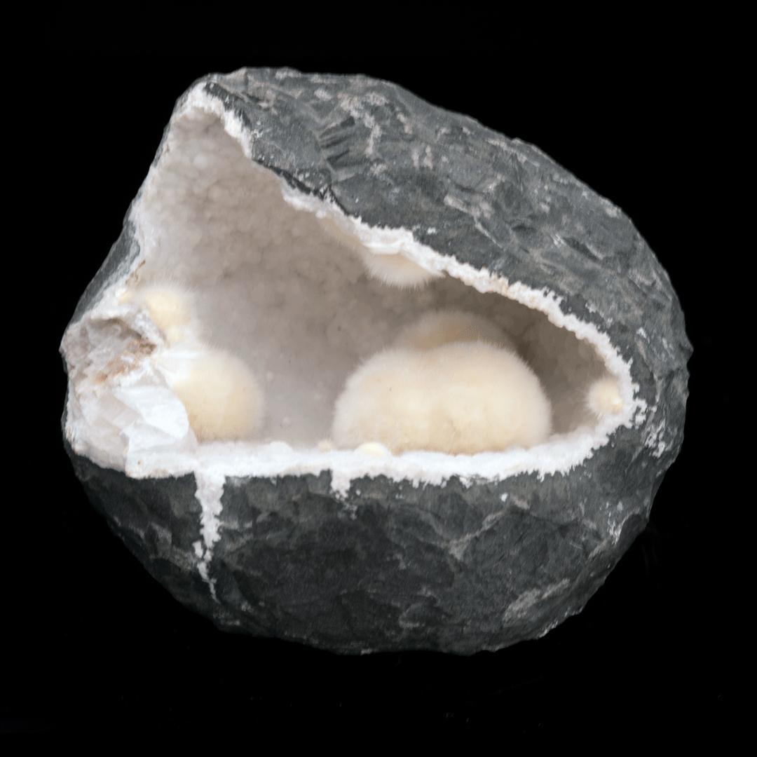 This hollow geode with a naturally rough, matte exterior is lined with the rare silicate mineral gyrolite growing with near-perfect tufts of fiber optic-looking okenite which are in actuality radial sprays of the needle-like crystals. A textural