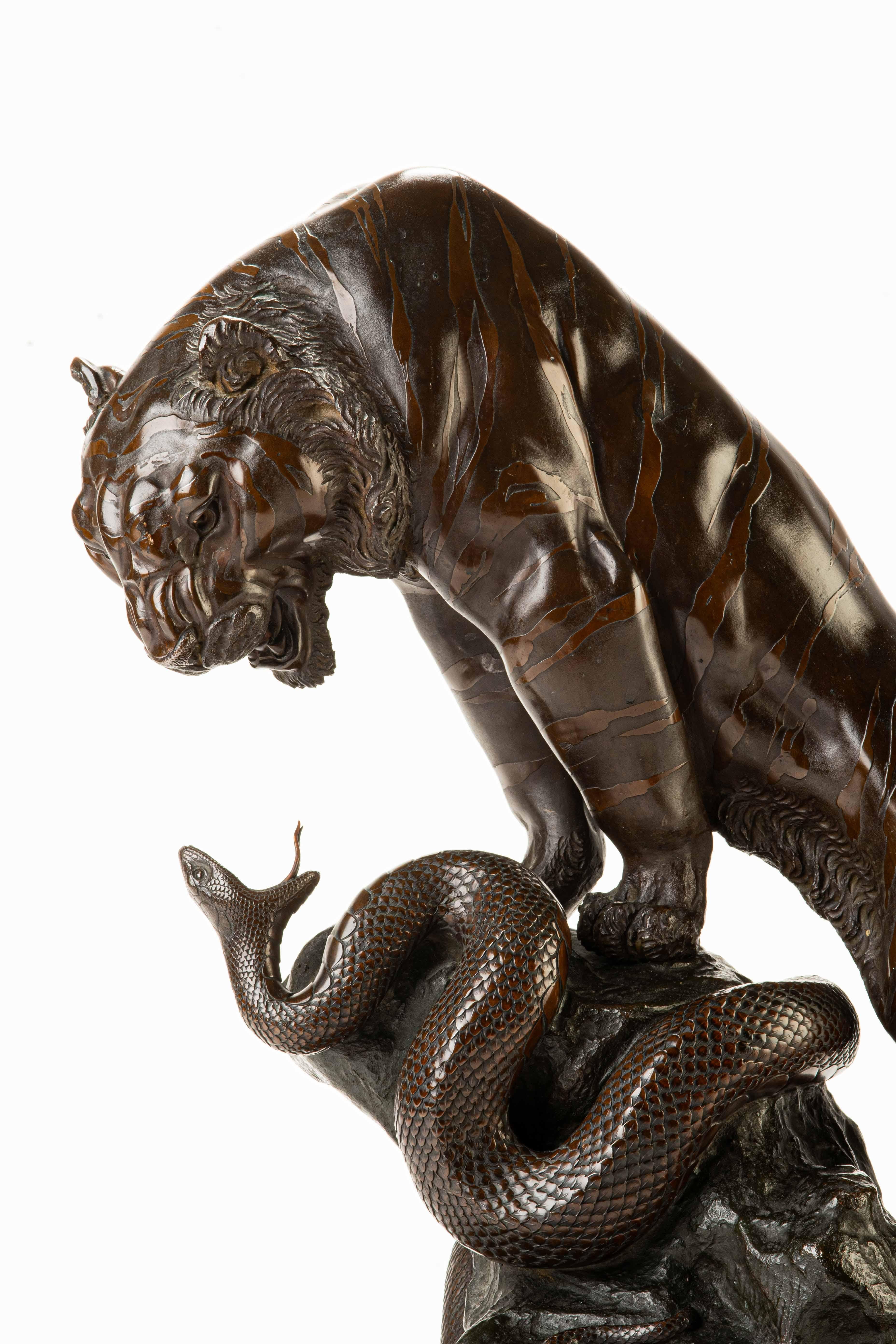 Okimono de bronce patinado que representa un tigre y una serpiente firmado Genryusay Seiya zo. Los animales, colocados frontalmente, están representados con las mandíbulas abiertas en un enfrentamiento directo.

Obra publicada en el volumen