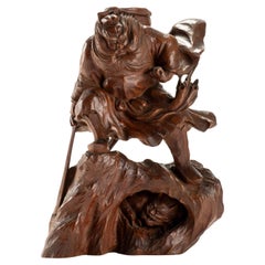 Okimono in legno raffigurante Shōki intento a sorprendere un oni