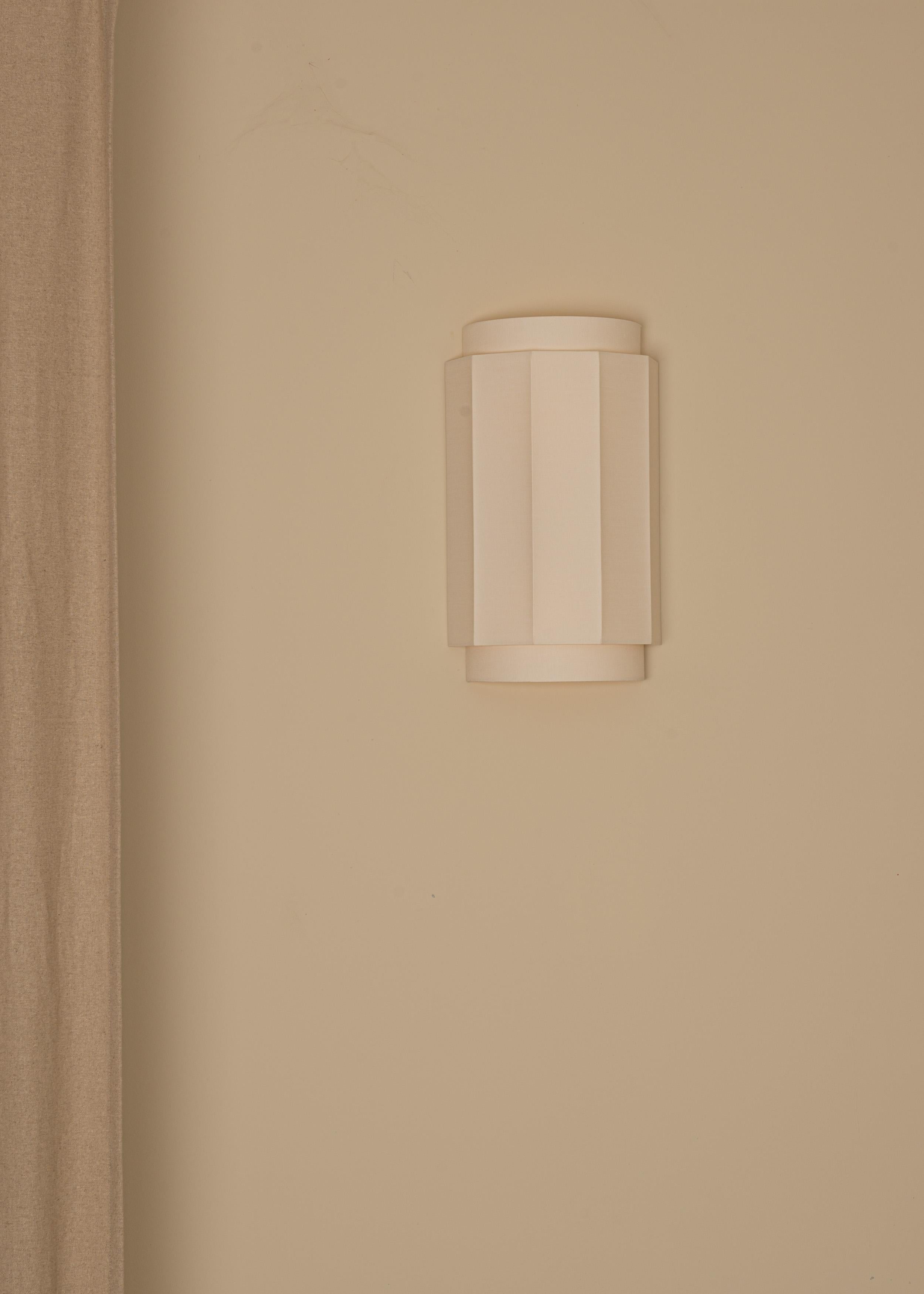 Geometries and superpositions creating a pure yet exceptional design. Okla is a wall light bringing purity and minimalism letting the light diffuses through a cotton double wall.