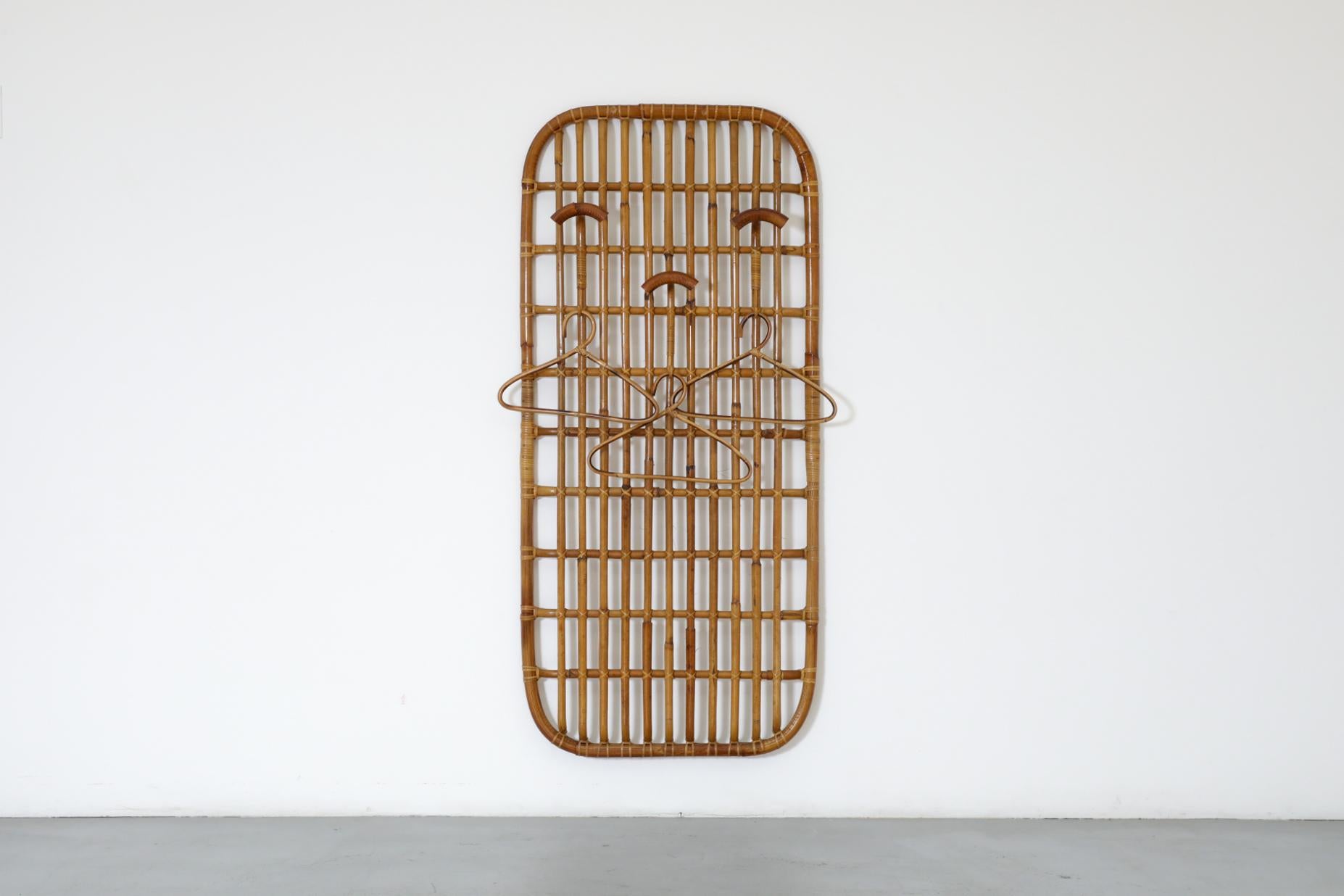 Italian Mid-Century, wall mounted bamboo coat rack with hooks and rattan accents in the style of Franco Albini. In original condition with a handsome patina and visible wear. There is minimal bamboo breakage. The wear is consistent with its age and