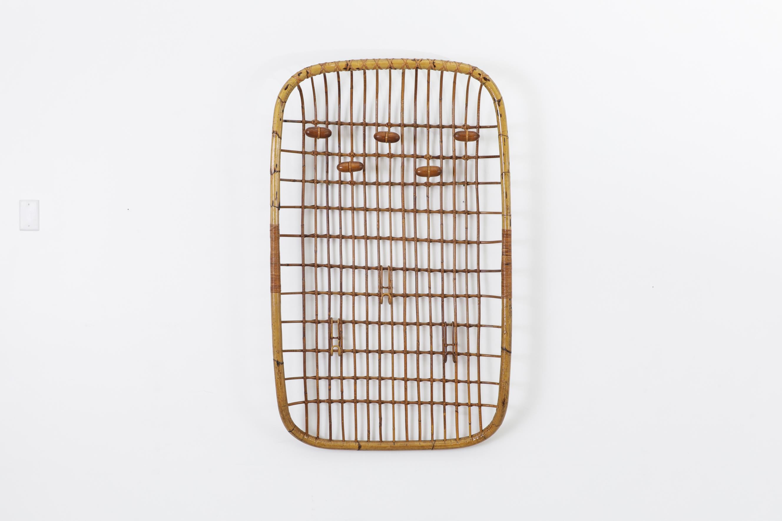Wall mounted bamboo coat rack with hooks and rattan accents by Olaf Von Bohr for Bonacina. In original condition with a handsome patina and visible wear. There is minimal bamboo breakage. The wear is consistent with its age and use.