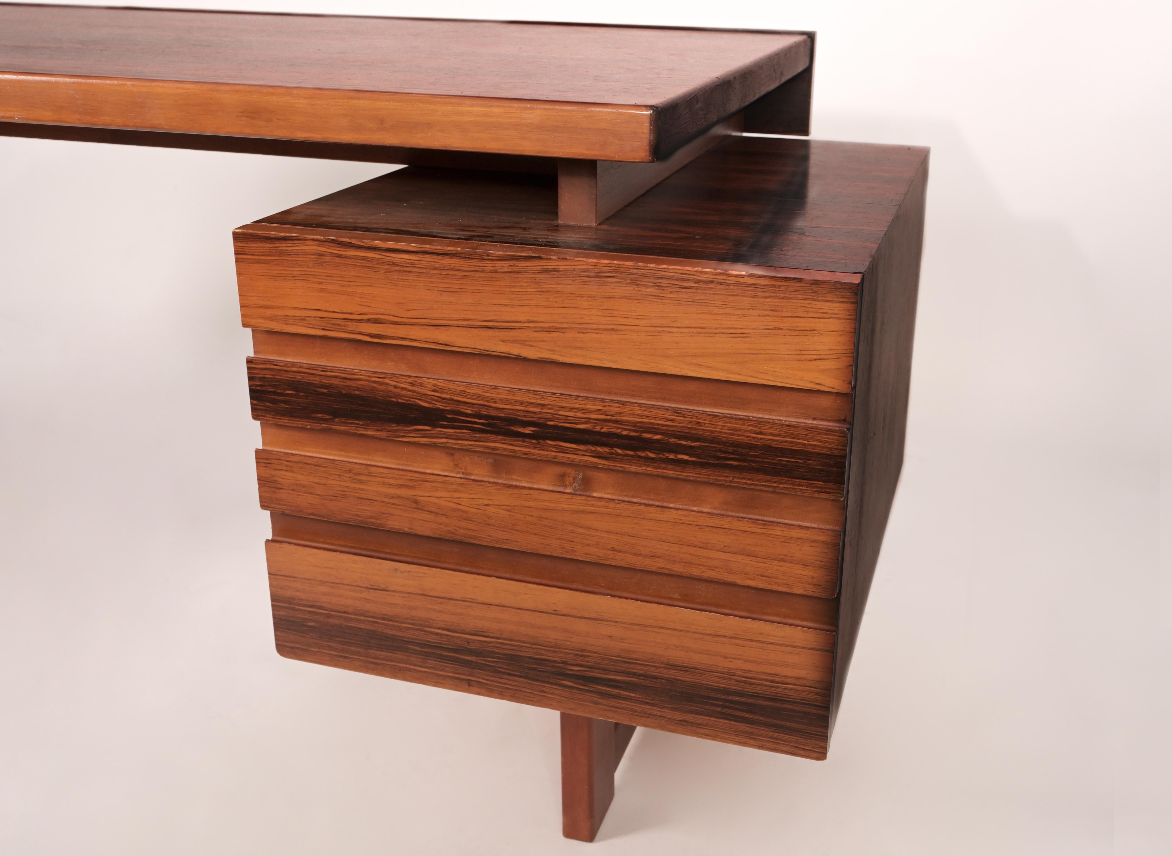 A Scandinavian Modern desk with highly figured rosewood veneered carcass. Designed by Olavi Hänninen (Finnish 1920-1992) for HMN Huonekalu Mikko Nuppone, Lahti 1960s. Veneered in Rio Palisander.  The knee hole opening have four drawers on either