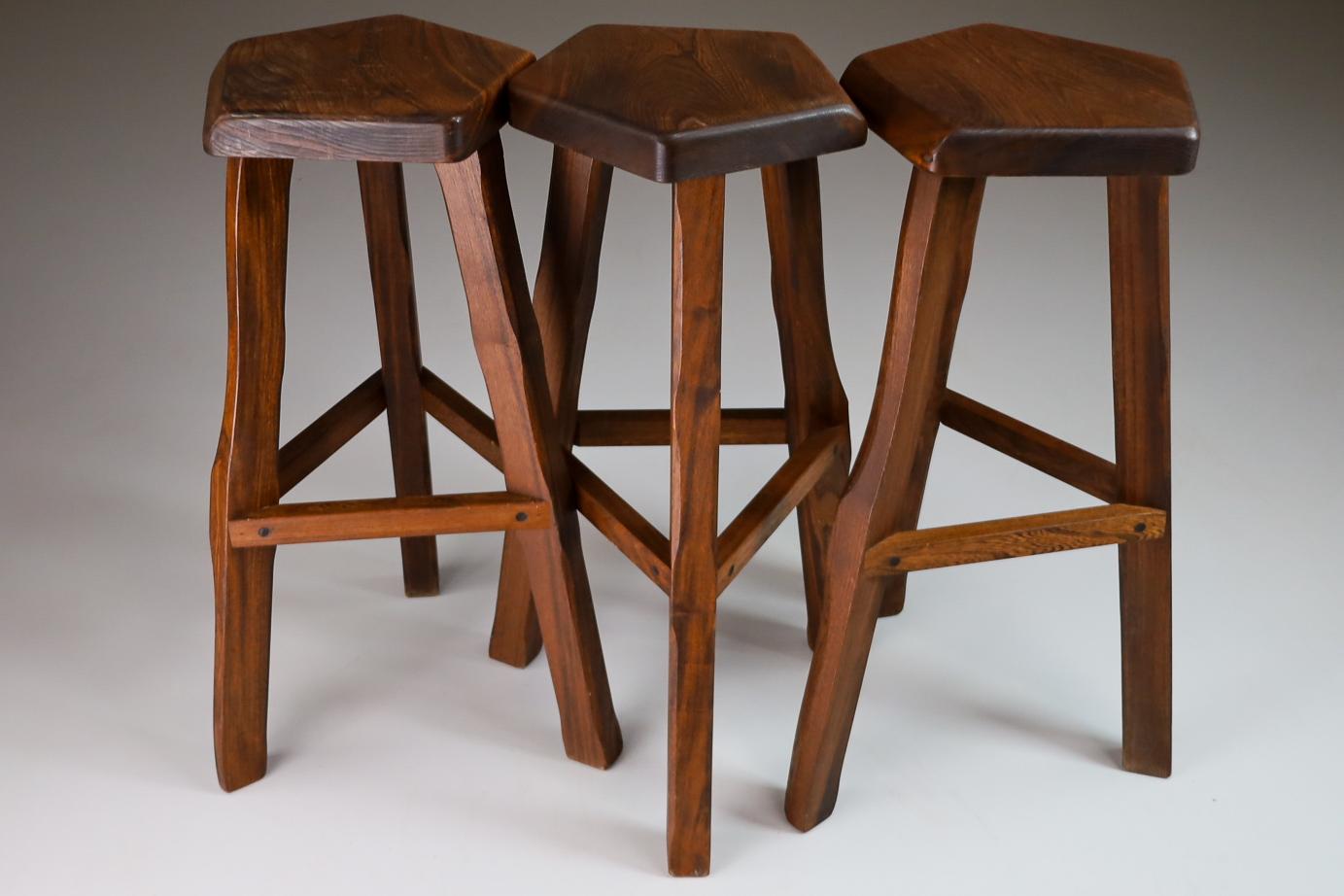 This set of organic modern stools by Olavi Hänninen has been made by hand from solid elm. A thick pentagonal seat sits on top of three splayed legs braces midway down. The edges of all the wooden pieces have been smoothened giving them a softer look