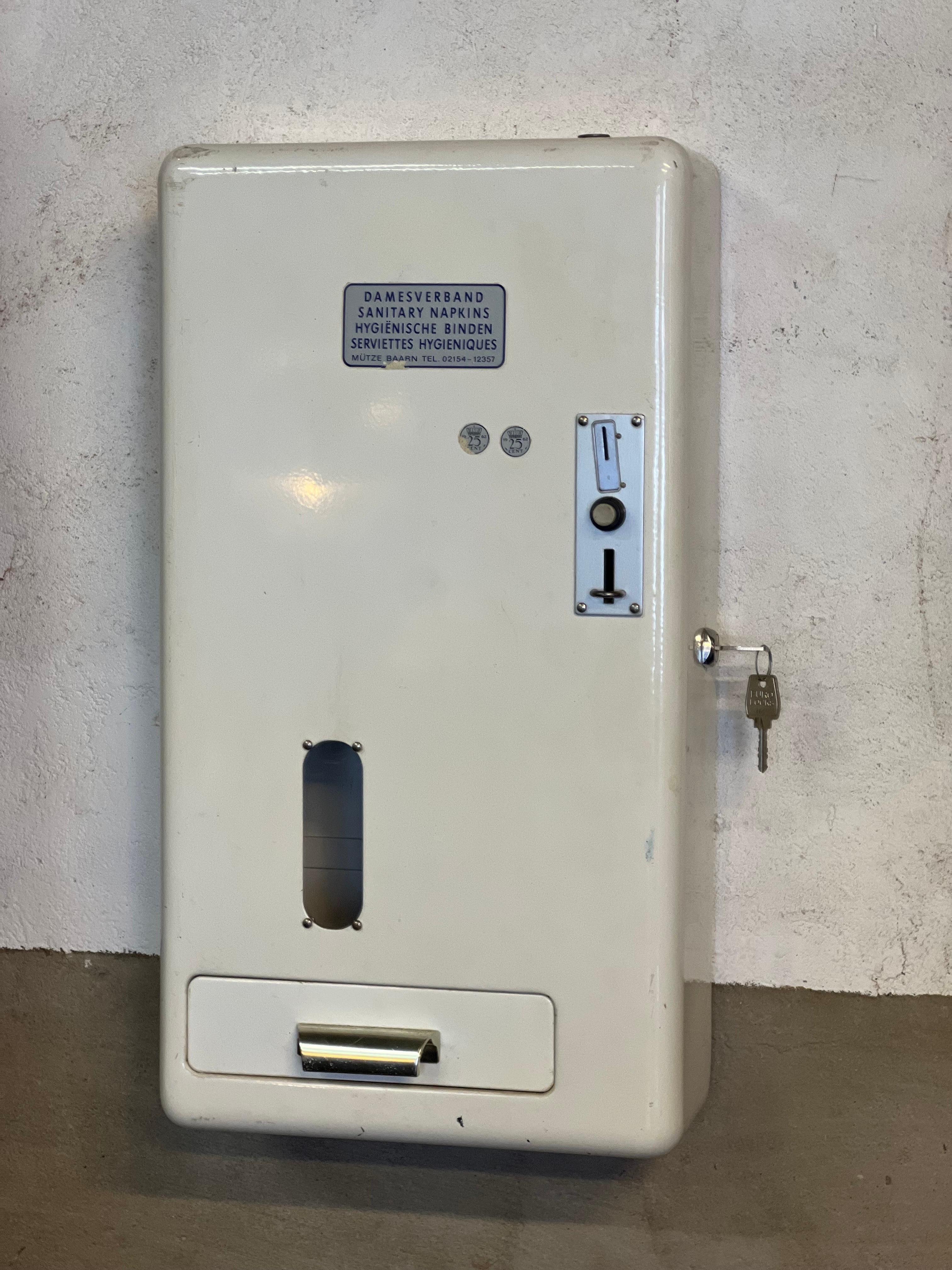 Un bel objet à accrocher au mur. Il s'agit d'un distributeur automatique hollandais en état de marche datant des années 1960 pour les tampons hygiéniques / serviettes hygiéniques. Il suffit d'introduire 2 pièces hollandaises pour que le tiroir se