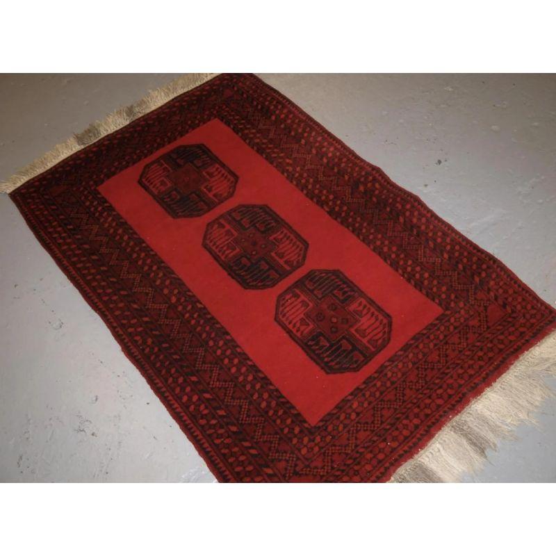 Old Afghan village rug of traditional design, the rug has a single row of 3 large Afghan guls.

The rug is a bright red colour with dark indigo blue / black. The rug retains the original short kilim end finishes at both ends with a long fringe.

The