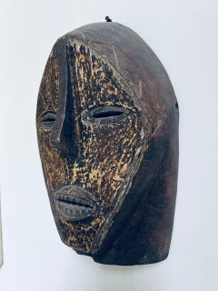 Antica maschera africana in legno pregiato e metallo, risalente al 1900 circa.