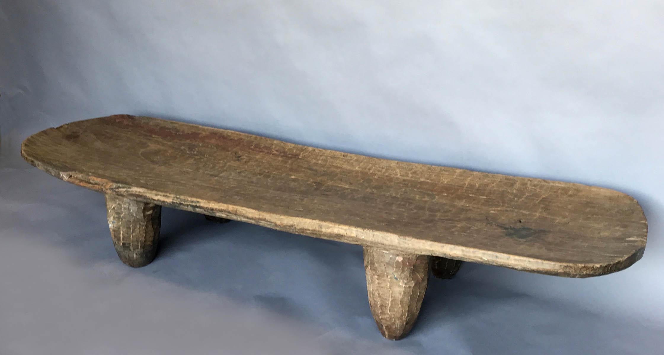Hand carved out of one piece of wood with conical legs and a rounded rectangular top. From the Nupe tribe of Northern Nigeria. Rich brown patina. A piece has been nicked off the side a long time ago.