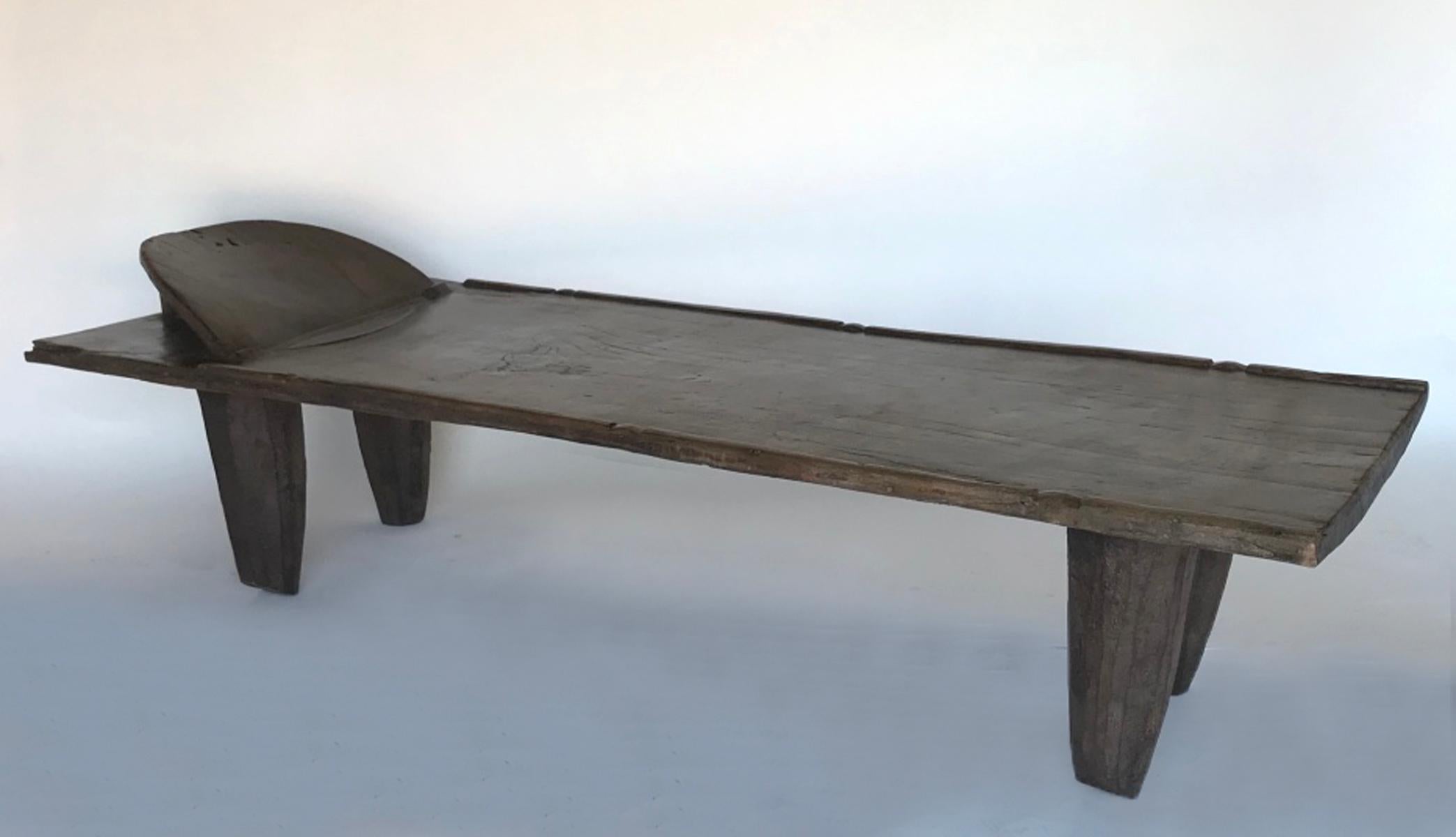 Old large wooden bed carved out of one piece of wood. Conical legs, headrest and carved detail on top. Beautiful, worn wood, smooth lovely patina. Mali. Legs and top all carved out of one piece of wood. Age appropriate wear, see photos. Top of