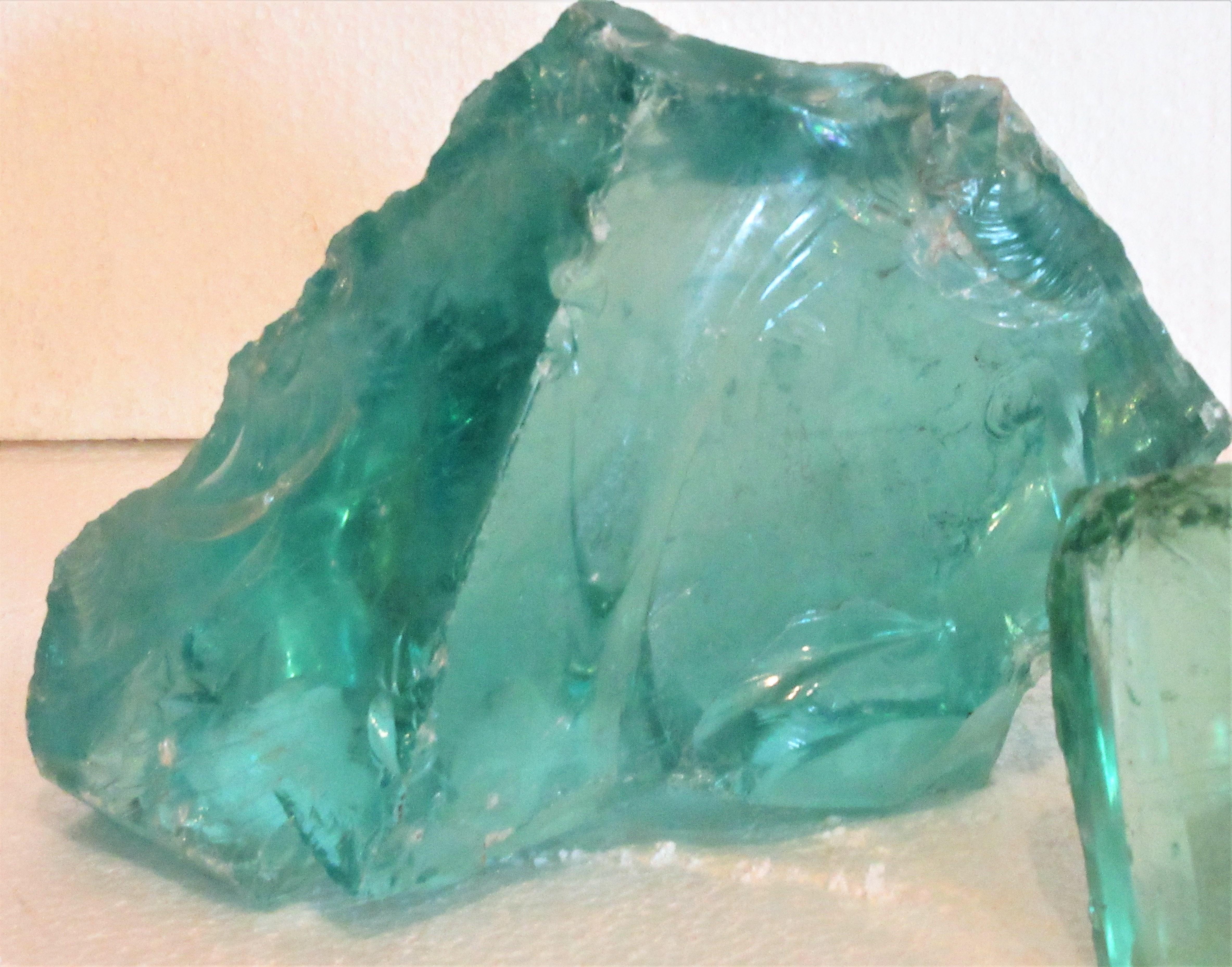 Two raw free form chunks of old factory glass cullet. Larger aqua - measuring as shown in images - 10 inches wide x 5 1/2 inches deep x 9 inches high. Smaller light green aqua - measuring as shown in images - 8 1/2 inches wide x 6 inches deep x 6