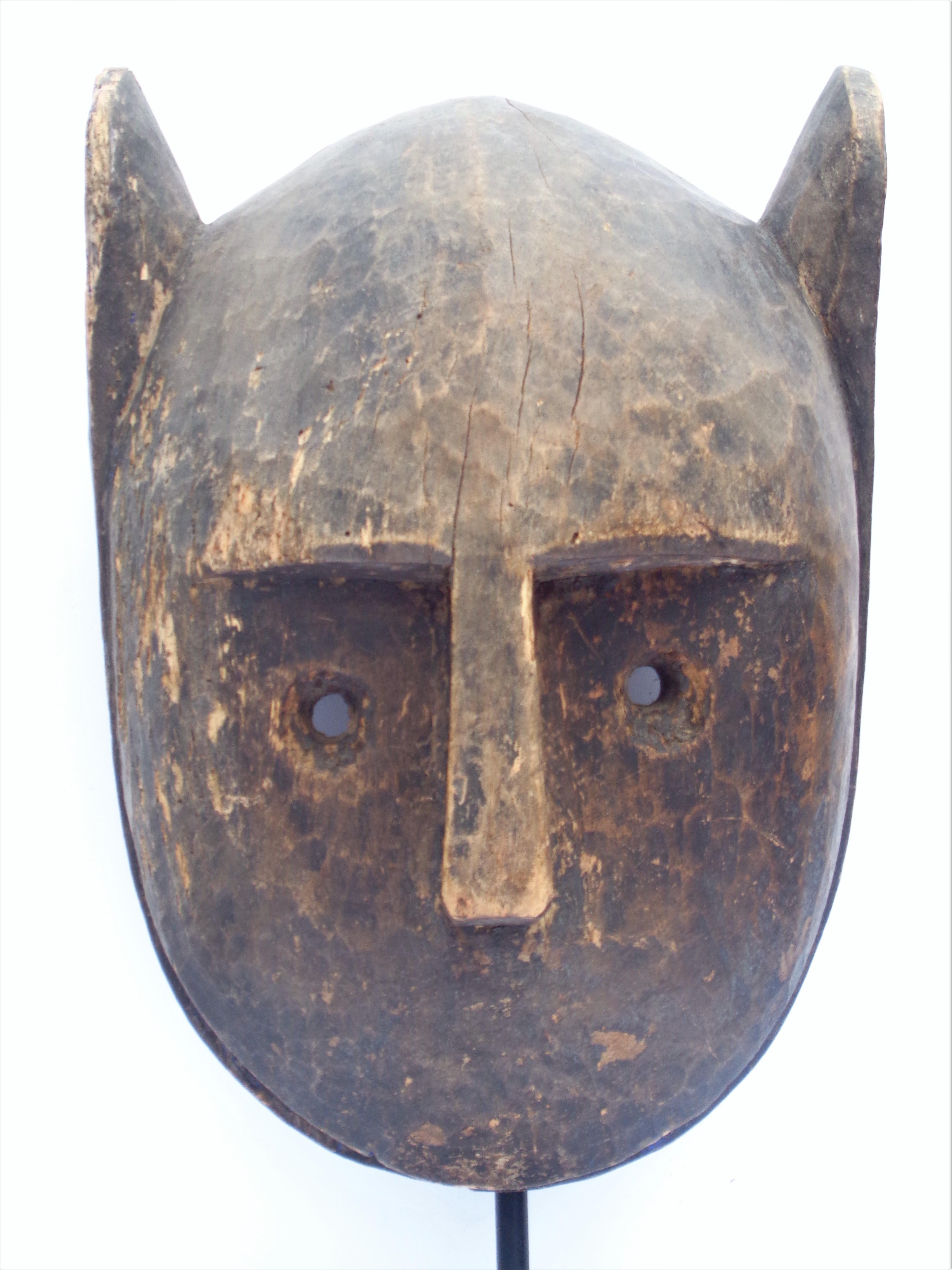 Bamana animal mask, Mali - representing a lion with short wide ears and open toothy mouth. A simple form with great presence in beautifully aged original old surface color with genuine wear and some old insect damage. Mounted on a fine custom black