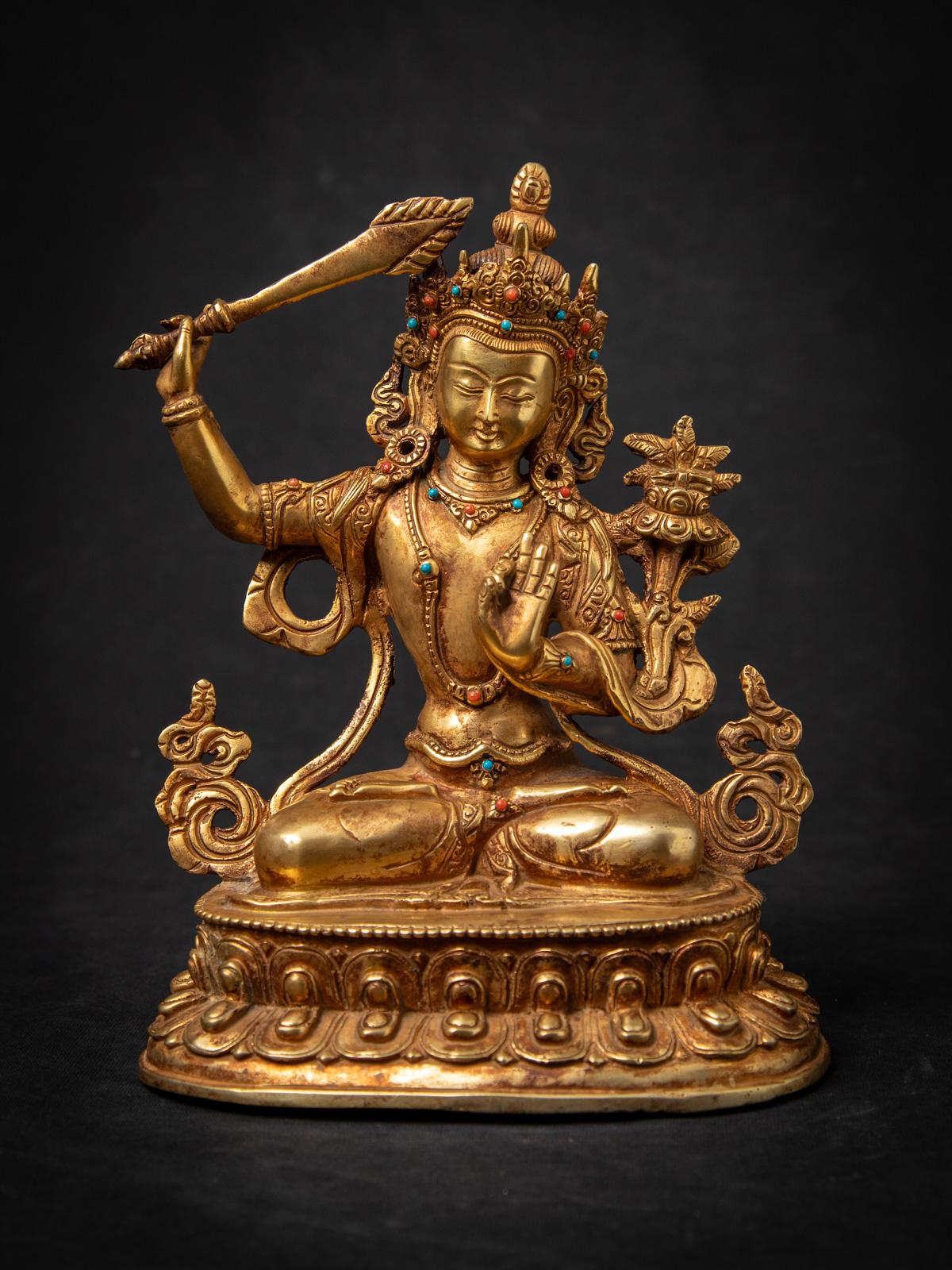 Questa antica statua di bronzo nepalese di Manjushri della metà del XX secolo è una notevole rappresentazione della saggezza e dell'arte buddista. Realizzata in bronzo e dorata a fuoco con oro a 24 carati, la statua misura 22,5 cm di altezza, 17,1