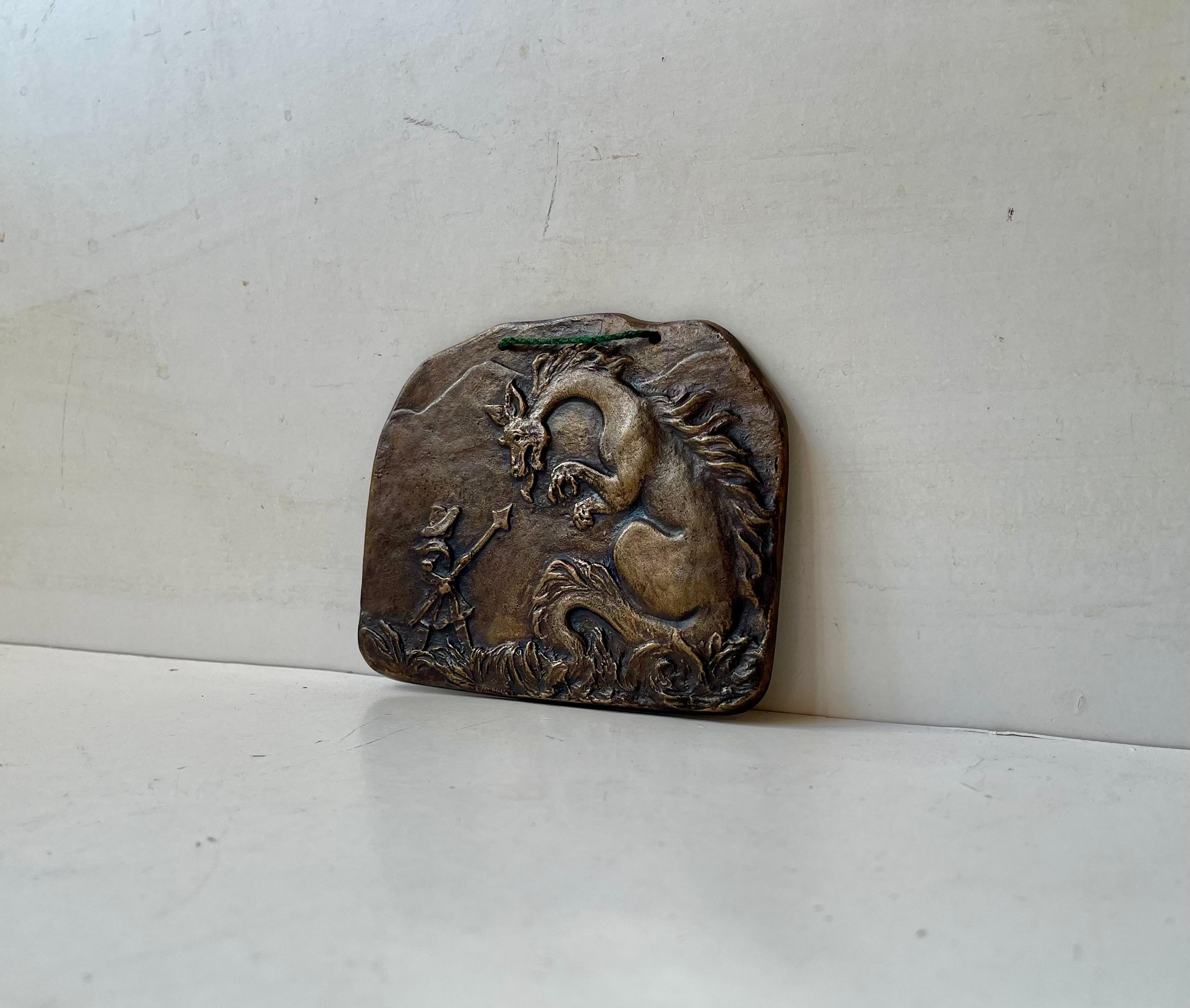 Ein interessantes mythologisches Thema wird in dieser kleinen Wandtafel vermittelt. Die Szene eines Drachentöters oder -jägers ist mit einem hohen Maß an Details aus massiver, patinierter Bronze gefertigt. Es wurde Anfang/Mitte des 20. Jahrhunderts