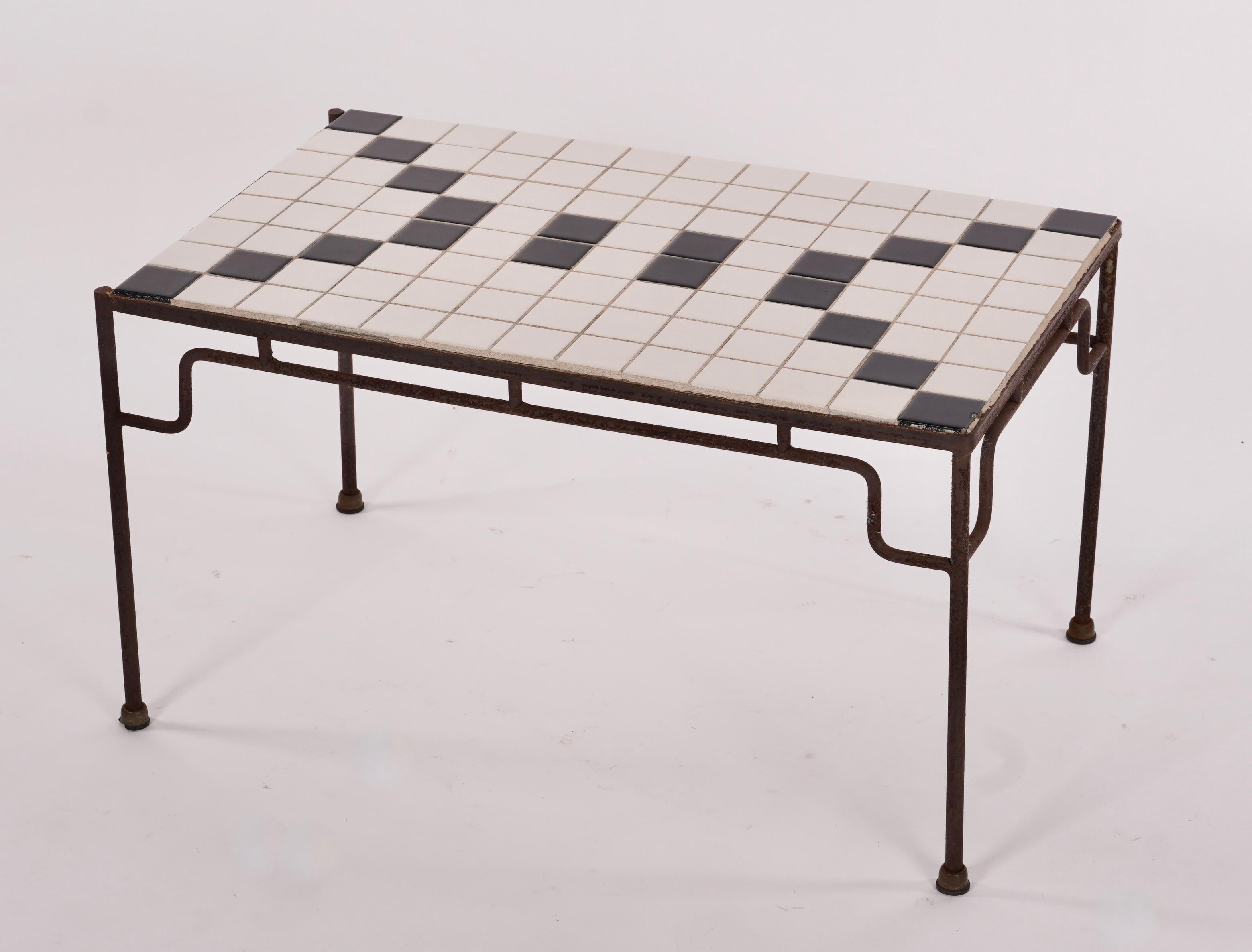 Petite table basse ou table d'appoint à structure en acier formée et soudée à la main avec des carreaux de céramique carrés noirs et blancs disposés selon un motif géométrique. Les lignes fluides du cadre en acier avec ses courbes douces créent un