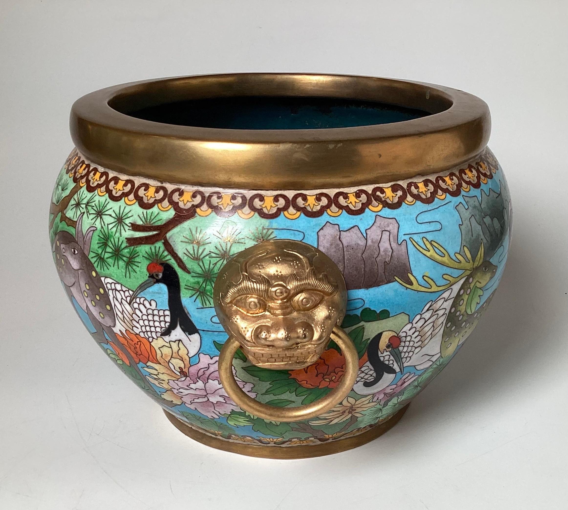Exquisitely detailed Chinese cloisonné jardinière with deer, cranes and floral decoration with gilt rims and Lion motif handles.  8.5 inches high, 14.5 inches wide, 11.5 inches deep..