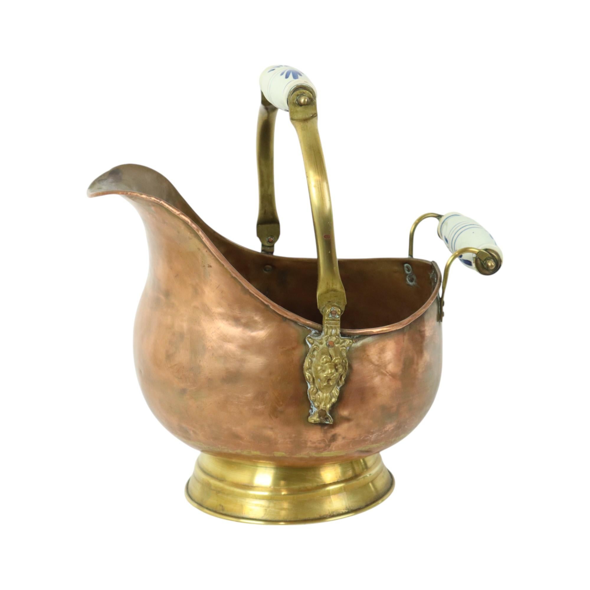 Nice and very old helmet-shaped coal scuttle made of red copper, brass and blue and white Delft handles, circa 1900, Netherlands.

This coal scuttle is very decorative and just a little bit better than all other copper coal scuttles, decorated along