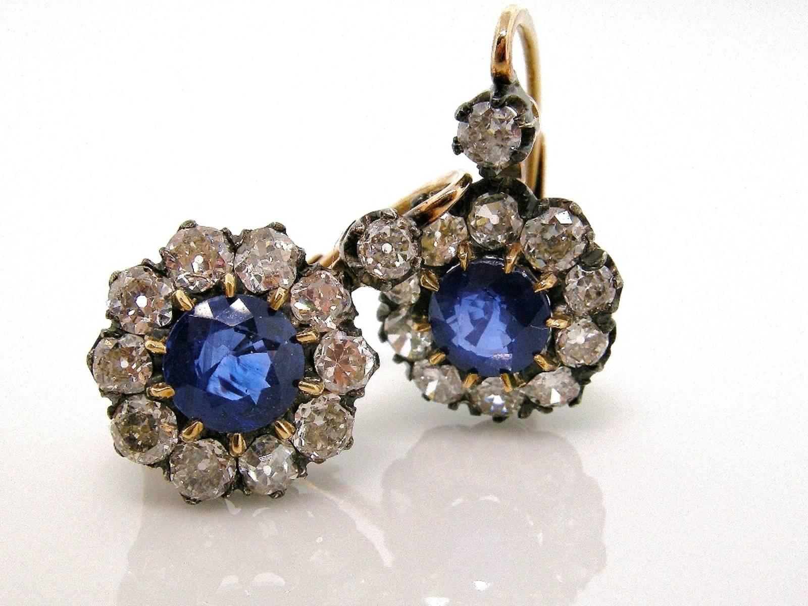 These shimmering hand made earrings are fabricated in Silver topped 18KT yellow gold.  The clusters center a round cut Ceylon Sapphire, both weighing 1.60 carat;  and are surrounded by ten Old Mine Cut Diamonds.  Old Cushion Cuts enhance the top of