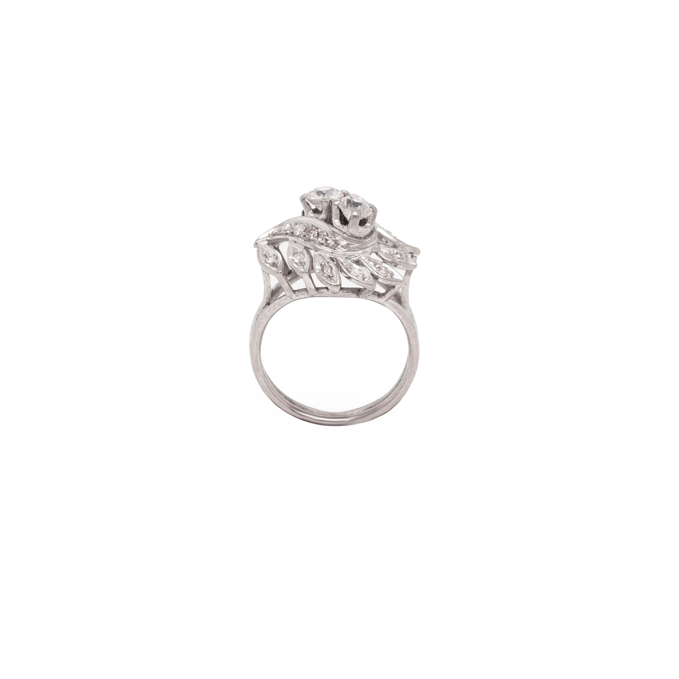 This wonderful cocktail ring showcases an elevated leaf-shaped design set in the centre with two old cut diamonds, mounted in four claw, open back settings. The ring is further designed with two twisted bands and delicate leaves, all inlaid with