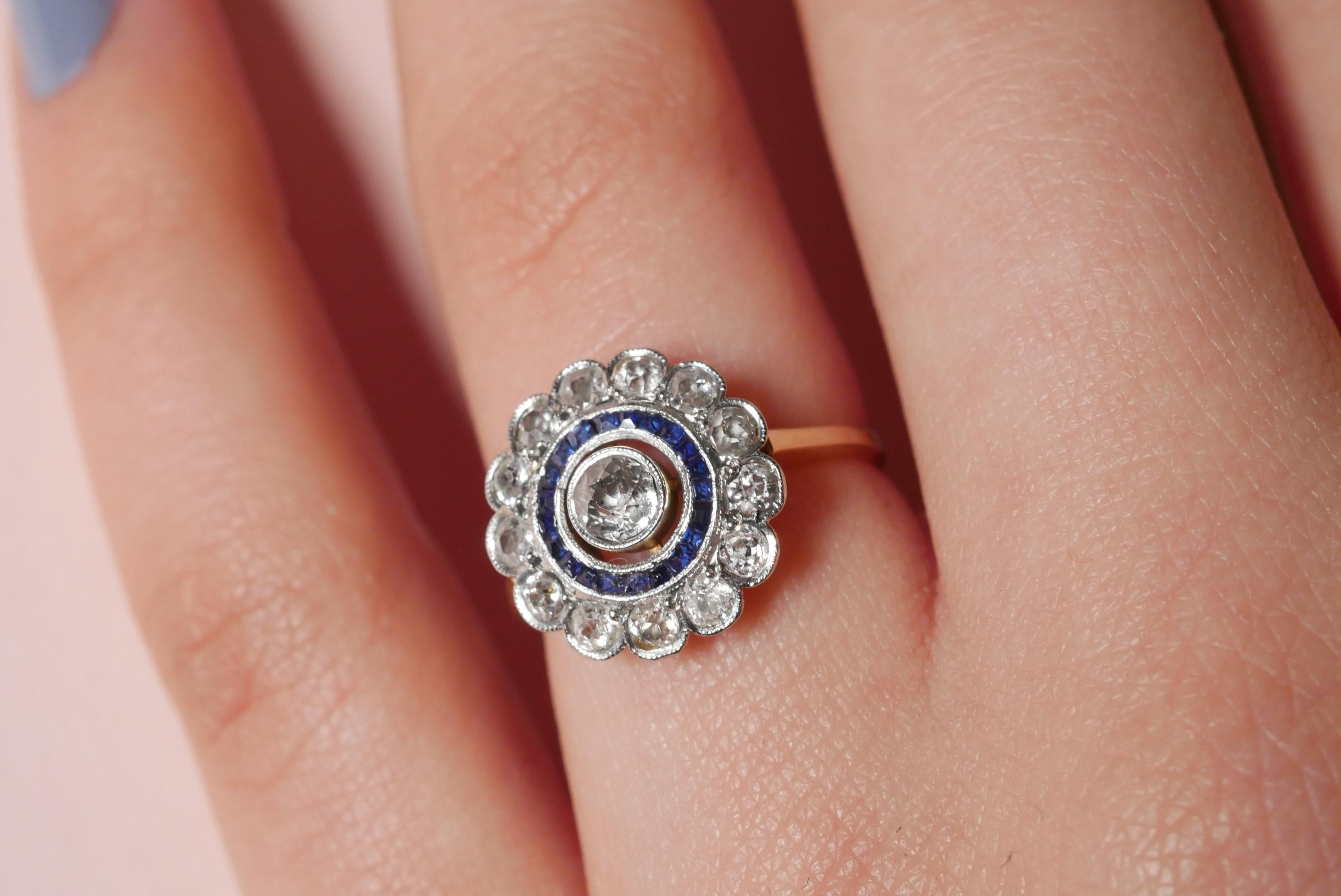 Handcrafted ring in yellow and white gold with a mesmerising old cut diamond in the centre, surrounded by a halo of blue sapphires and a halo of round diamonds in a beautiful open back setting.

Ring Size: UK - J 1/2, US - 5
