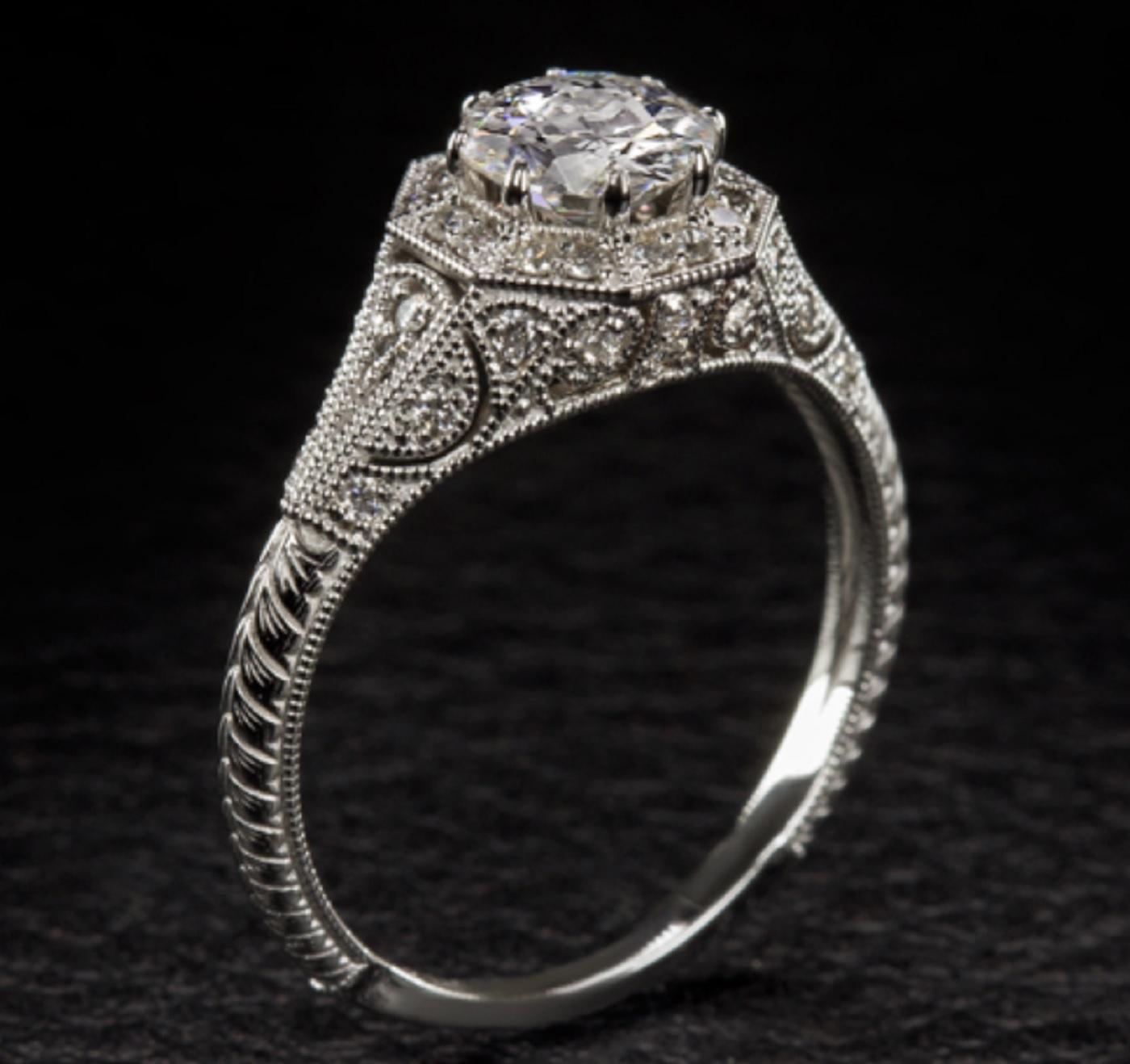 This richly detailed and timelessly designed vintage style ring showcases a stunning old European cut diamond richly accented by a romantic vintage style setting. Graded F for color, the 0.70 carat center diamond is colorless, a rarity in diamonds
