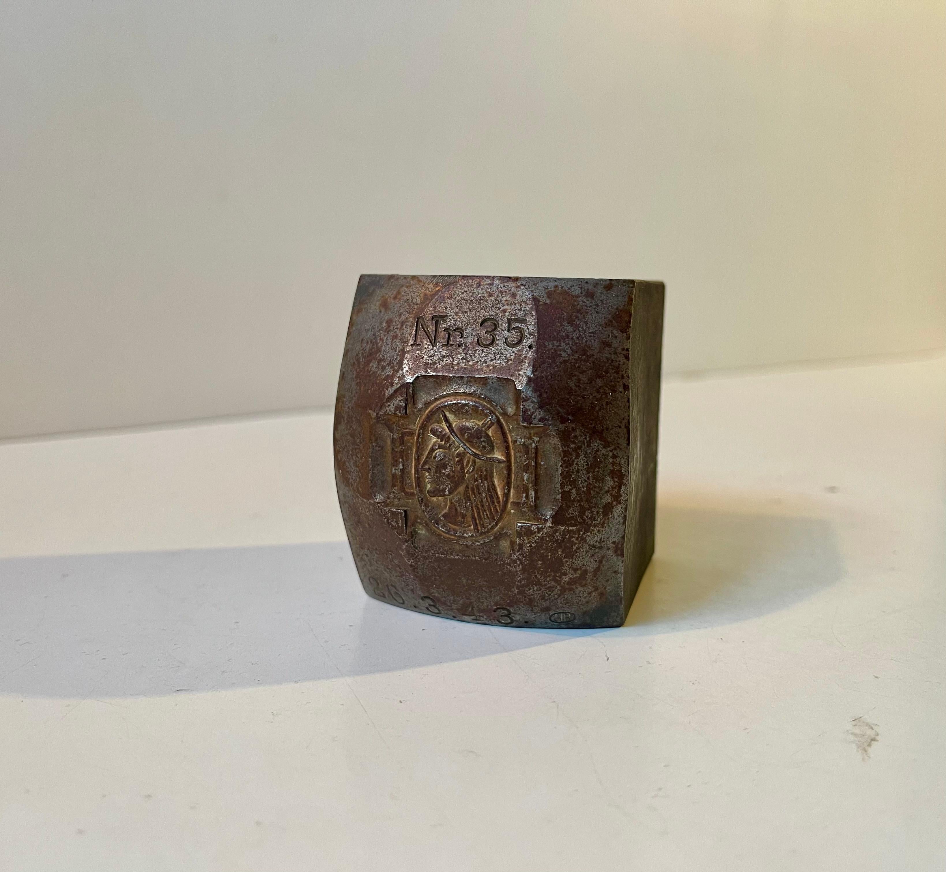 Non sappiamo molto di questo timbro/sigillo decorativo e pesante in ferro massiccio. Possiamo dire che è danese dalla scritta, ma per quanto riguarda il monogramma della testa non abbiamo trovato una corrispondenza. Presumiamo che sia militare o che