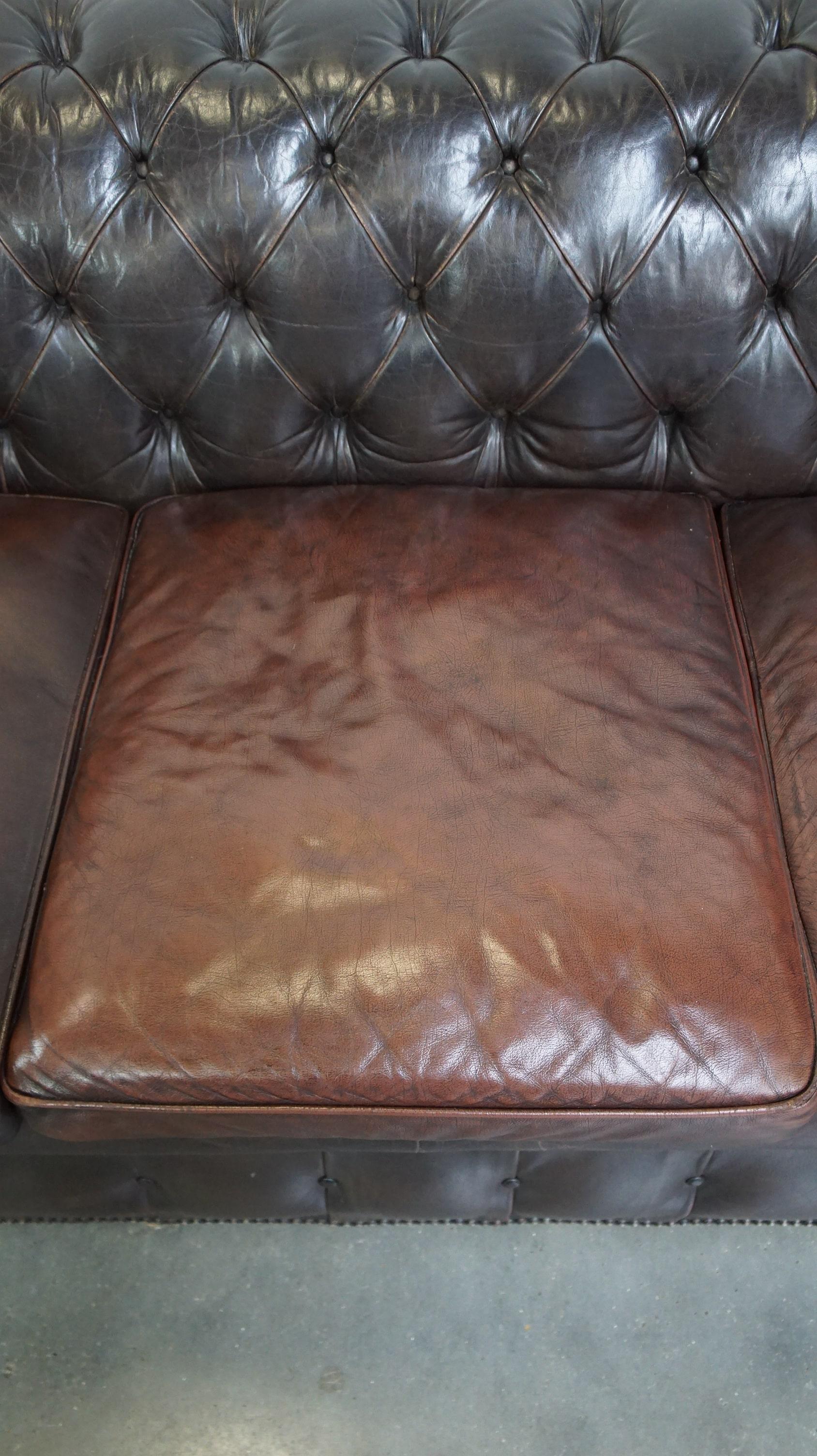 20ième siècle Ancien canapé Chesterfield 3 places en peau de vache brun foncé avec beaucoup de caractère en vente
