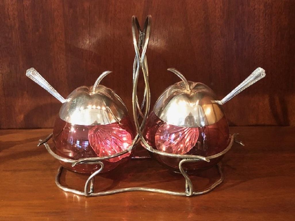 Add some fun to your table with this colorful Old Edwardian Apple Shaped Cranberry Preserve Pots with Silver Plated Tops, Spoons and Shaped Stand From England.