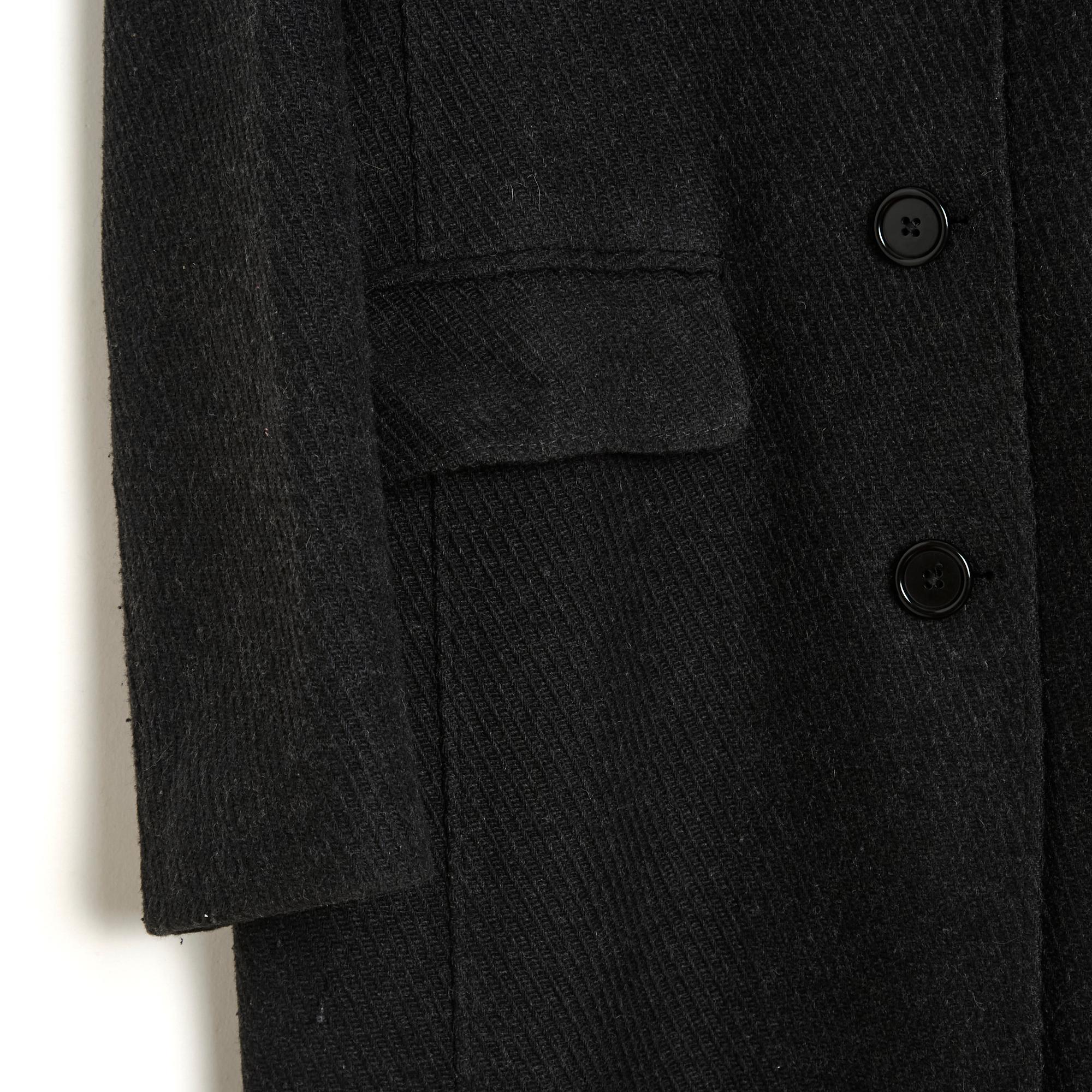 Old England Paris coat in polyamide and wool cloth with tone-on-tone herringbone patterns in anthracite, straight cut, small notched collar closed with 3 buttons, 2 flap pockets (one still closed), small slit at the back, black satin canvas lining.