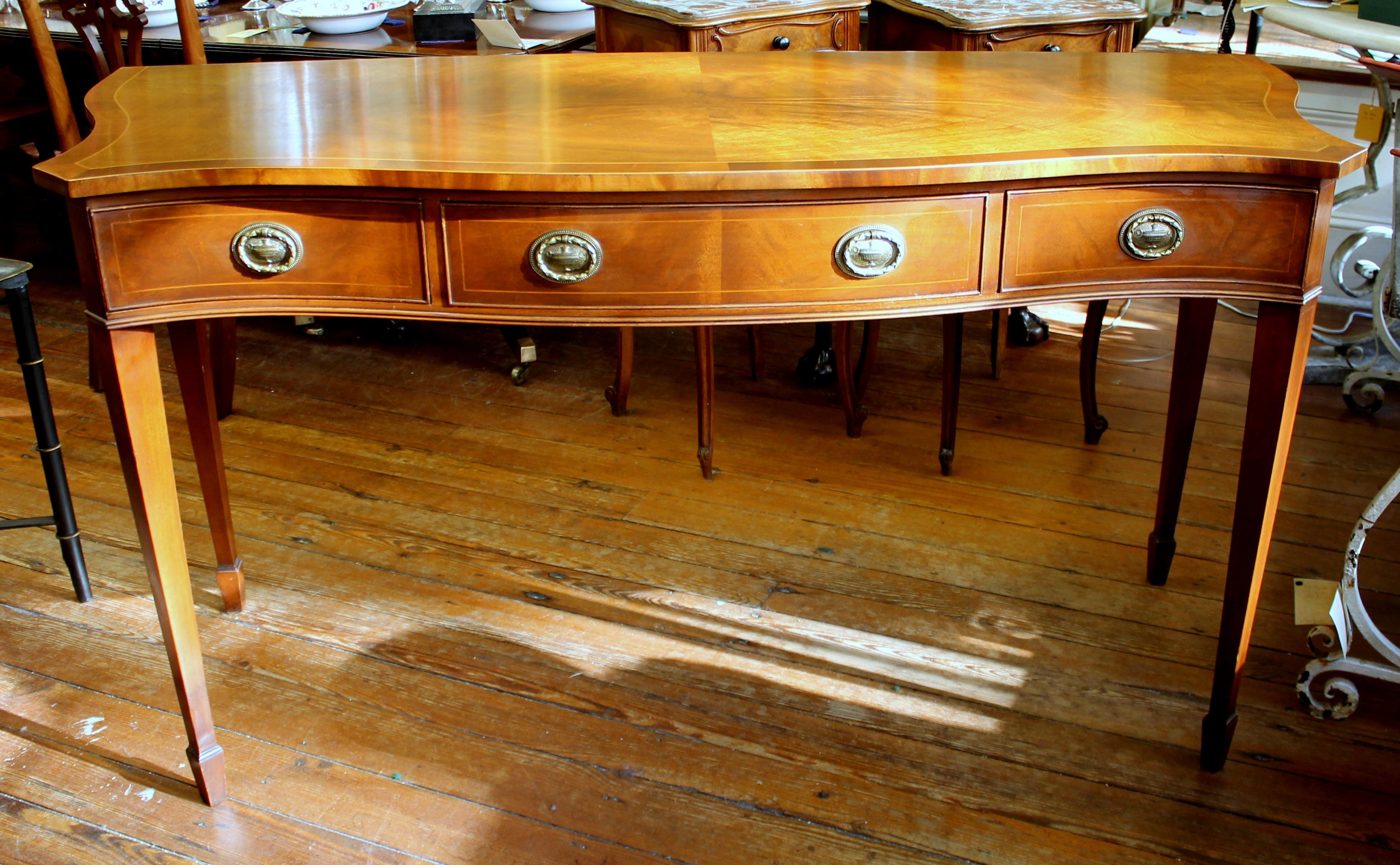 Very fine old English inlaid mahogany serpentine front hunt-board; the top being beautifully quartered with bookmatched highly figured flame or crotch mahogany in a handsome 