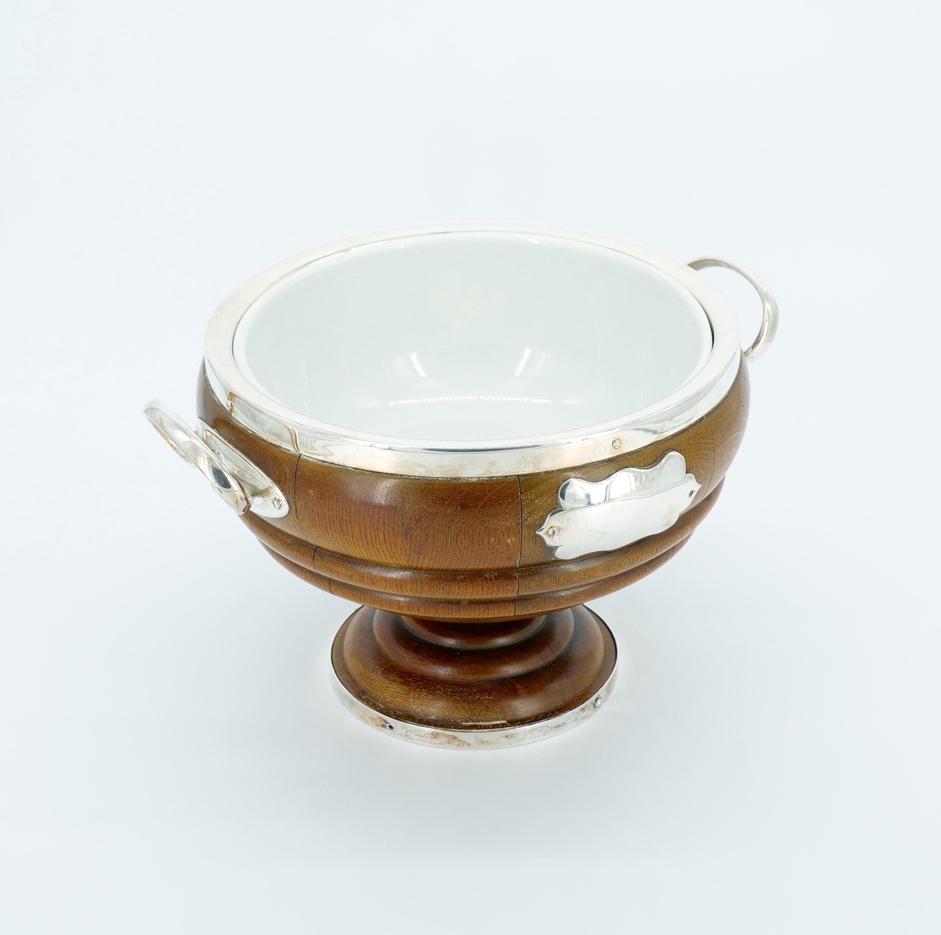 Elevate your table setting with this exquisite Old English Oak Exterior Holding Base and Porcelain Interior Decorative Serving Bowl. The timeless charm of this piece is evident in the meticulously crafted oak wood holding base, adorned with a silver