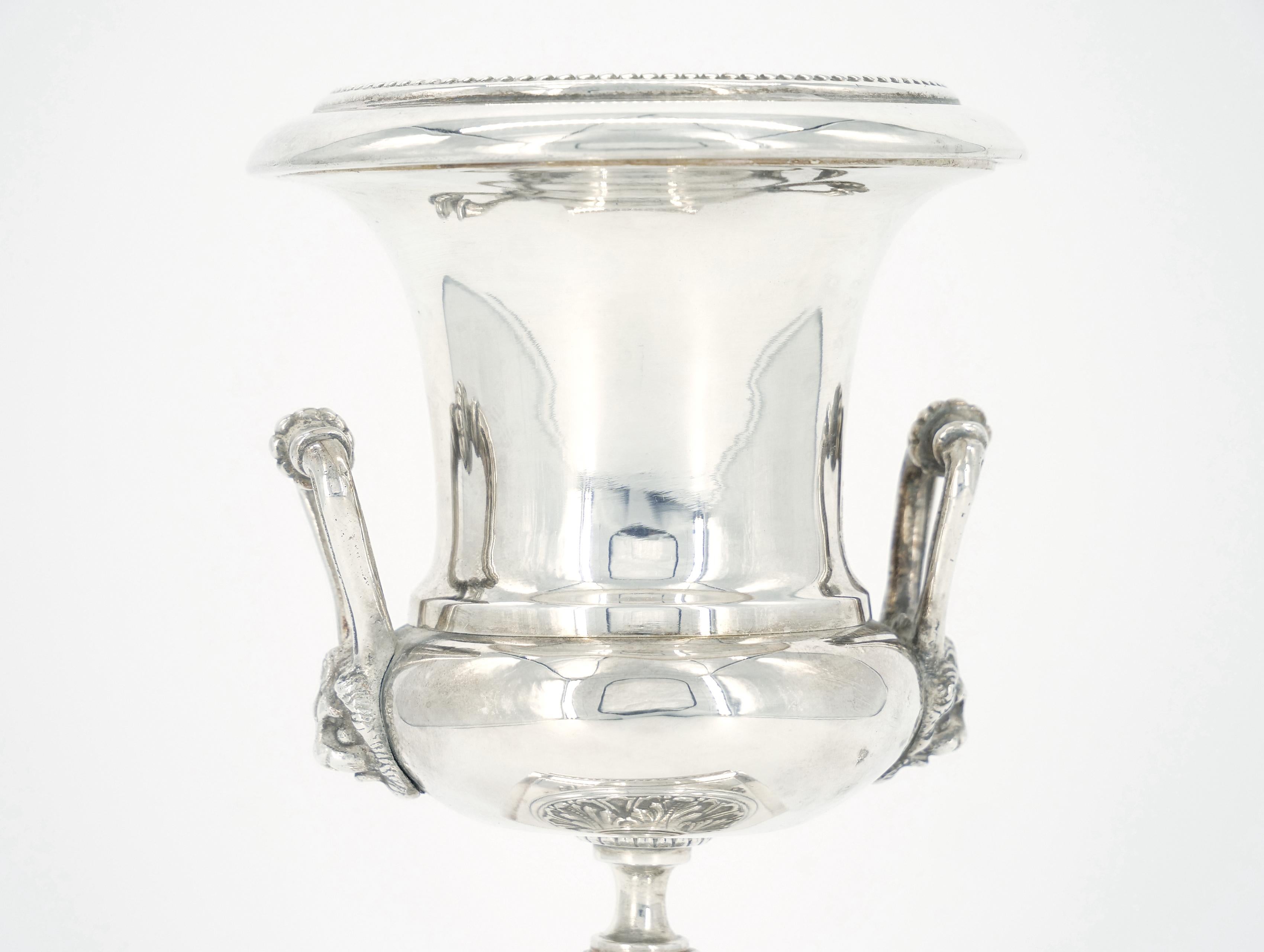 Discover the exquisite charm of our Old English Sheffield silver plated small decorative urn / vase with lion head side handle. This timeless piece , adorned with intricate detailing and a boasting footed square base , is a perfect fusion of
