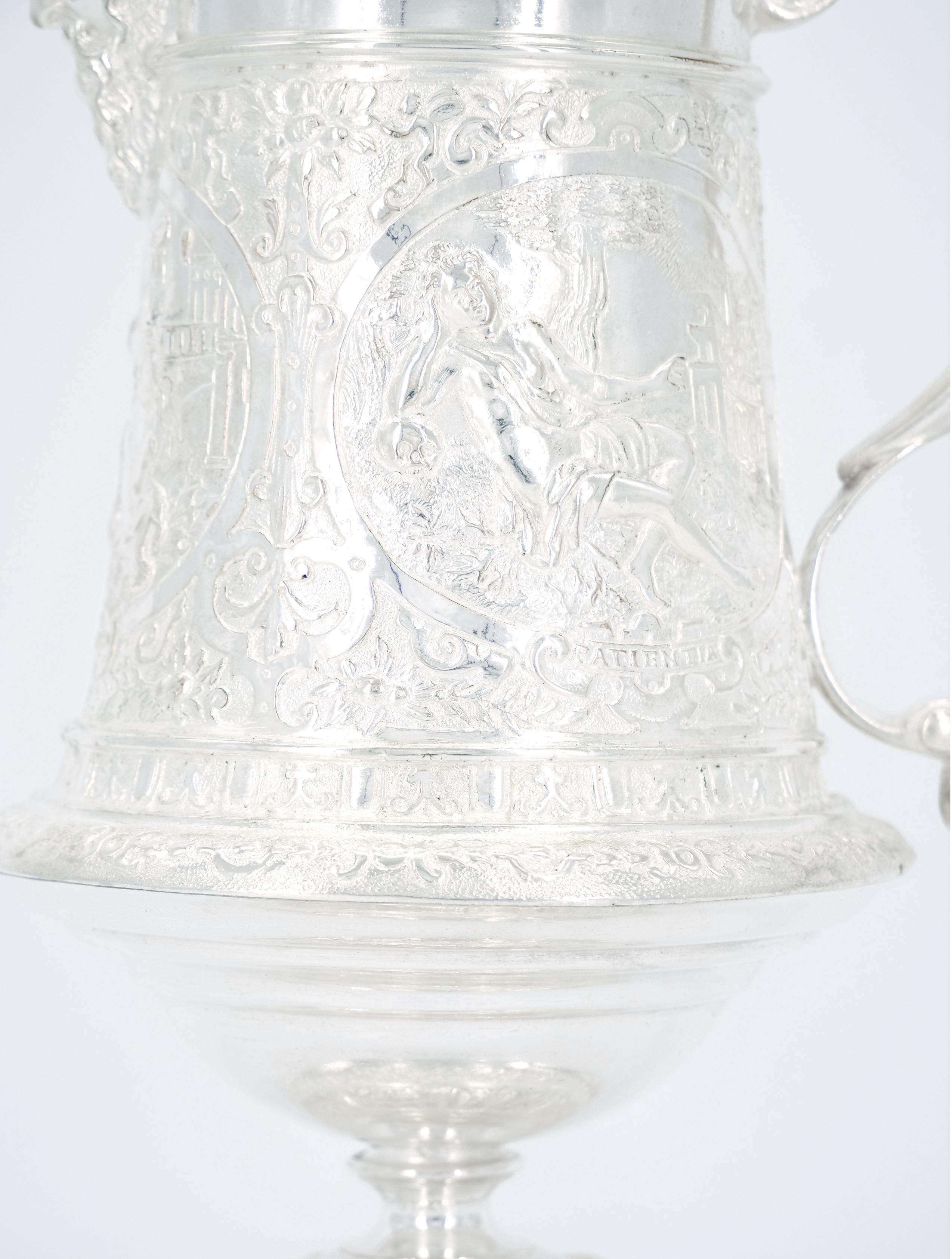 Late 19th century English silver plate barware / tableware serving jug by Joan Grinsell. The Jug features an attached covered finial top of a soldier with an heavily all over body hand decorated greek mythology goddess figures. The jug is in great