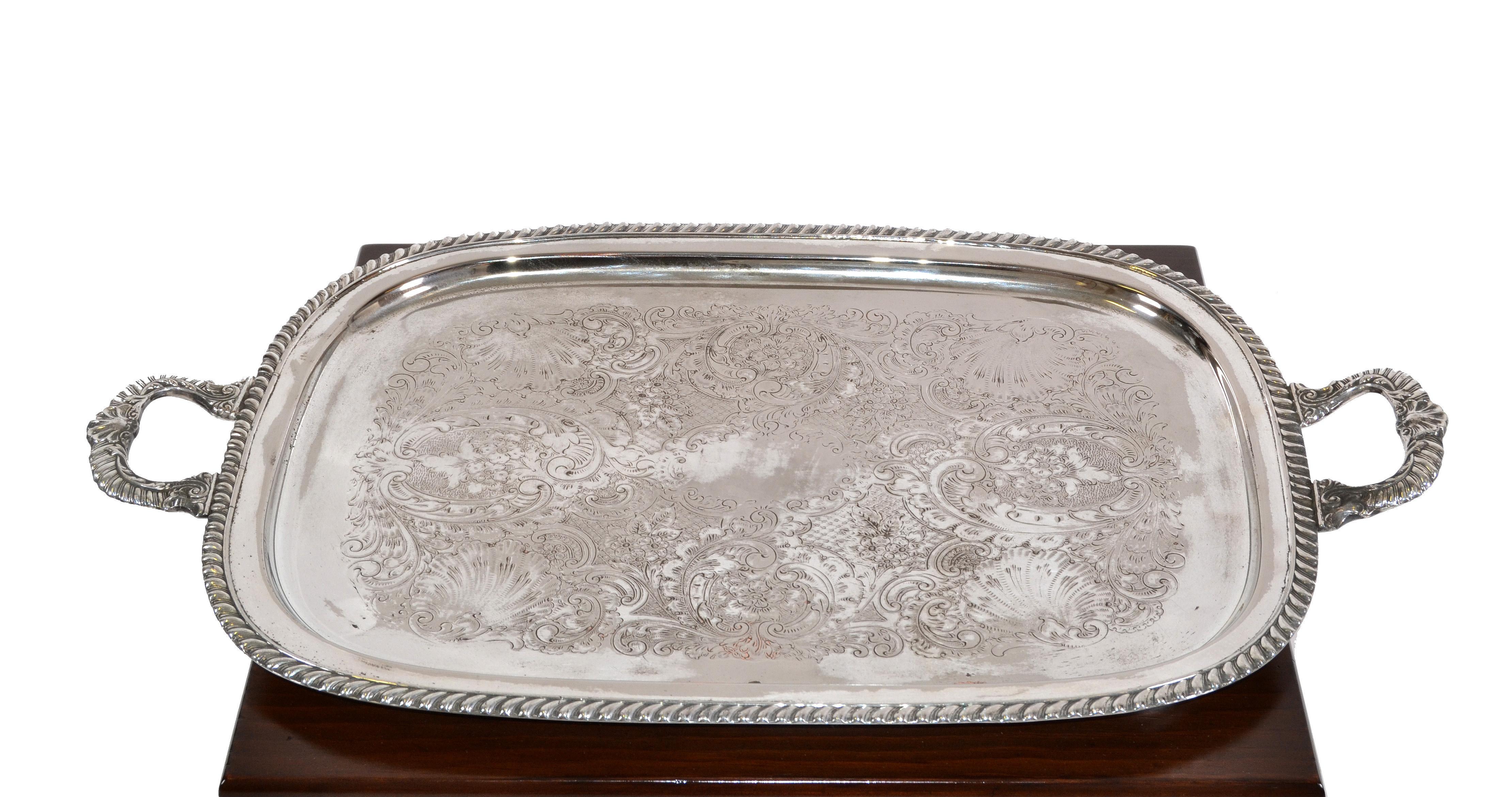 British Colonial style old English silver plate rectangular serving tray, platter with ornate handles. Scroll embossed in the Center. 
It is in original vintage condition and has some stains and is tarnished.
Measures inside tray: 20 x 14.75 x 1.75