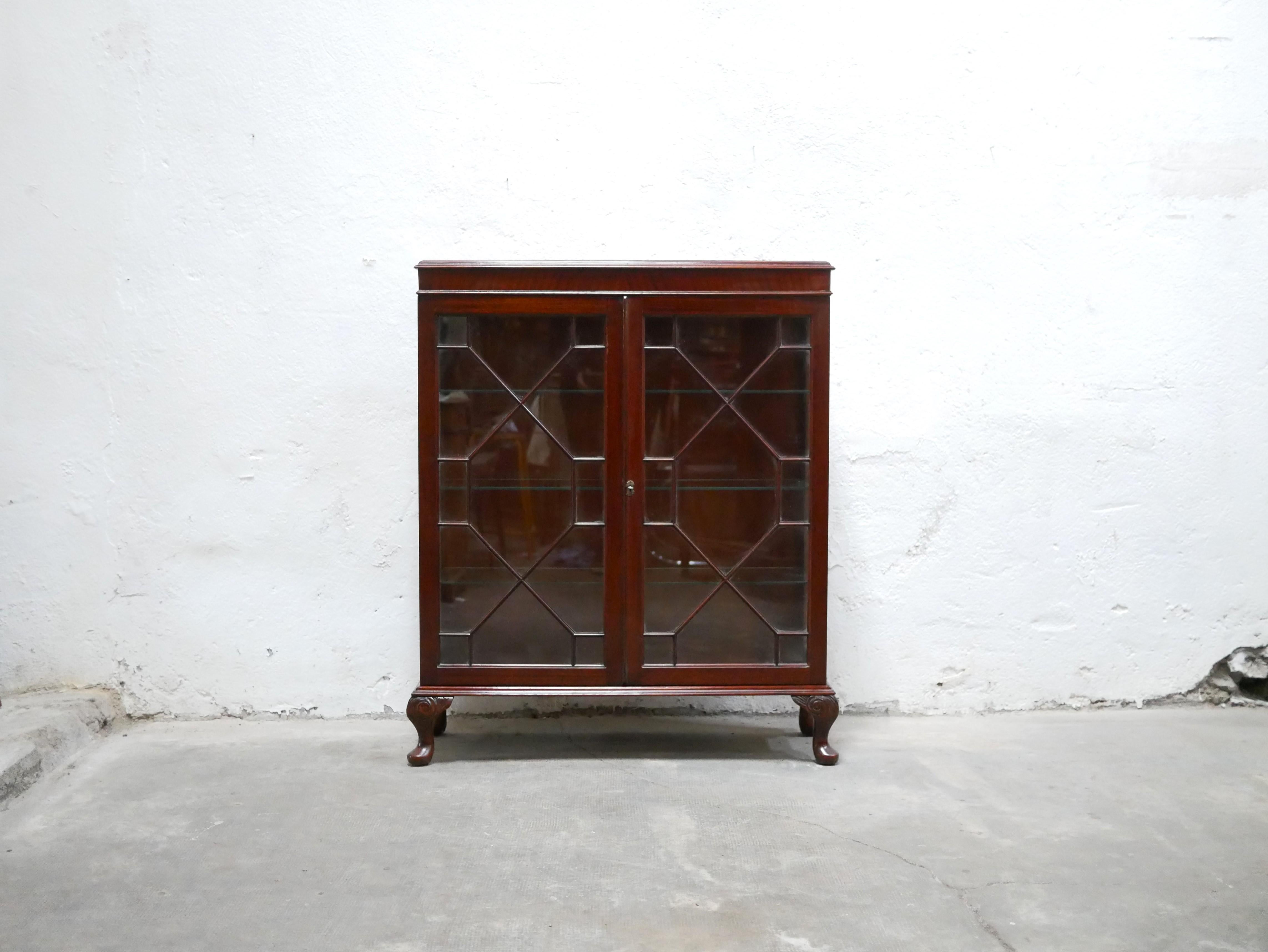 English mahogany display cabinet dating from the 1960s.

The color of the wood is bright and warm. Its small size, its glass doors adorned with wooden strips, the curve of its legs and its glass sides give it a lot of character and elegance.
