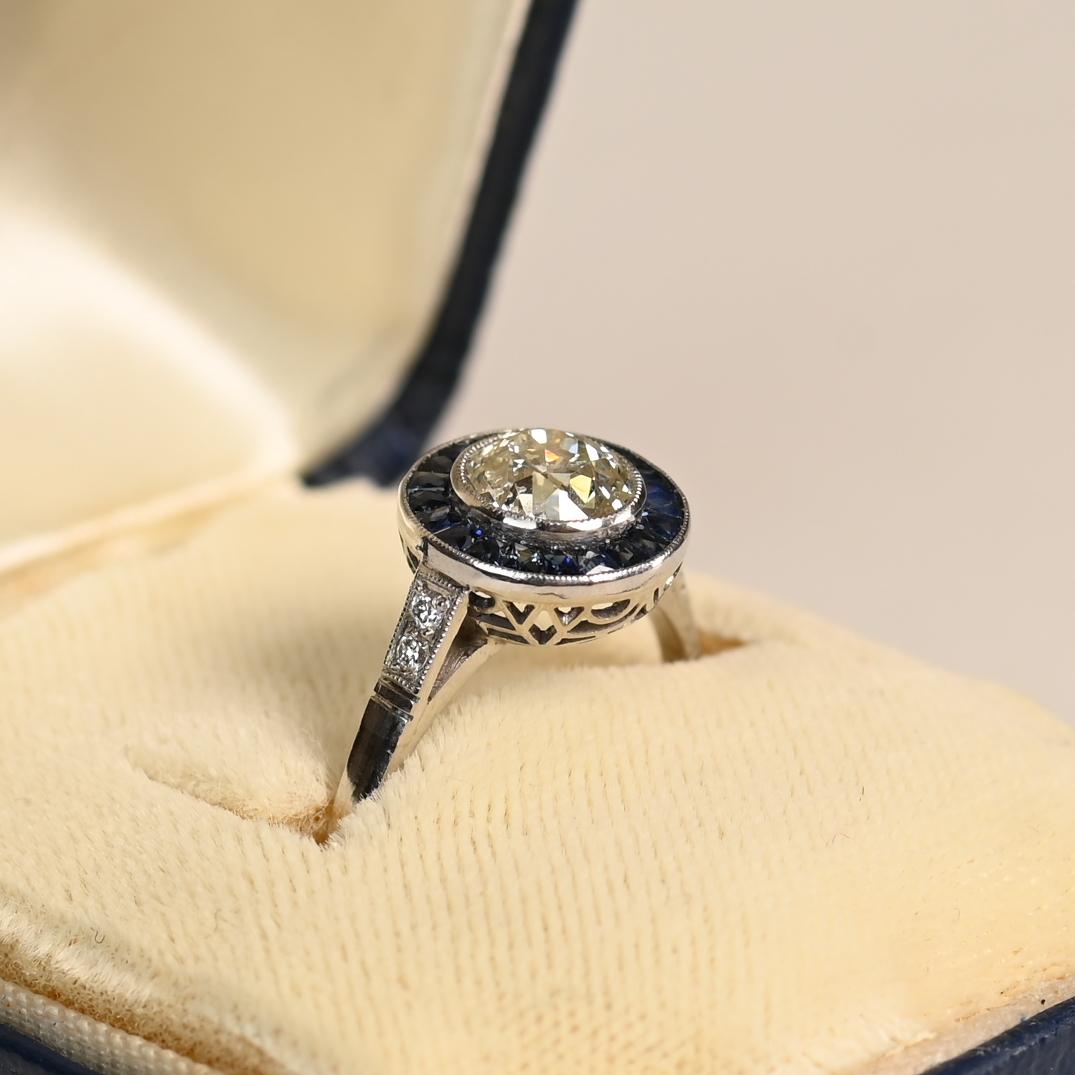 Este exquisito anillo de compromiso con halo exhibe un diamante de talla europea antigua engastado en bisel, con un peso aproximado de 1,00 quilates, color K y claridad SI1. La piedra central irradia una elegancia atemporal, acentuada por un halo