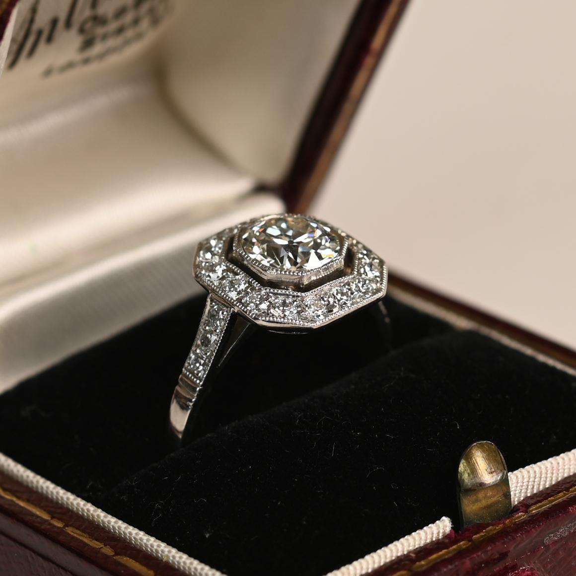 Este exquisito anillo de compromiso geométrico de platino exhibe en su centro un impresionante diamante de talla europea antigua de aprox. 1,00 quilates, clasificado K en color y VS2 en claridad. La pieza central está bellamente enmarcada por un