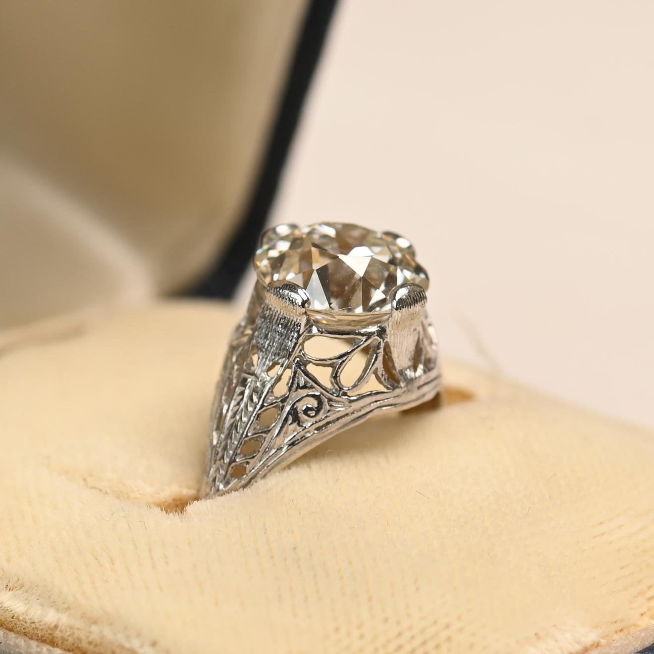This exquisite Art Deco ring features a GIA-certified old European cut diamond weighing approximately 3.00 carats. The diamond displays a warm J color paired with a clean VS1 clarity, making it a captivating centerpiece. Its brilliance is further