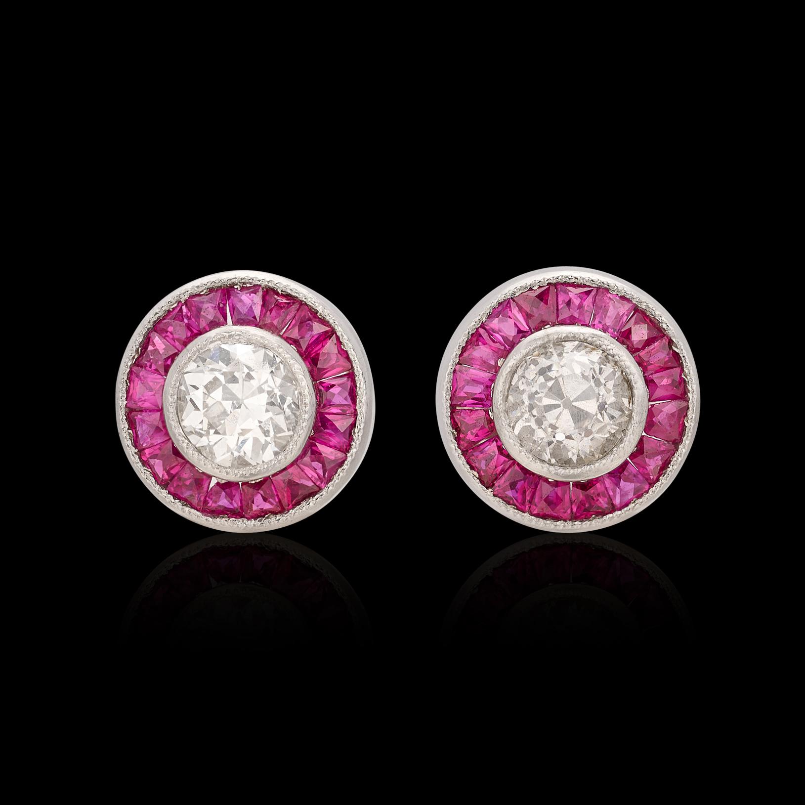 The perfect pair of diamond stud earrings surrounded by just the right amount of color. The platinum earrings feature two old euro diamonds (averaging I/SI1) for 0.30 carats, encircled by a halo of fine red rubies. The diamond stud earrings deliver