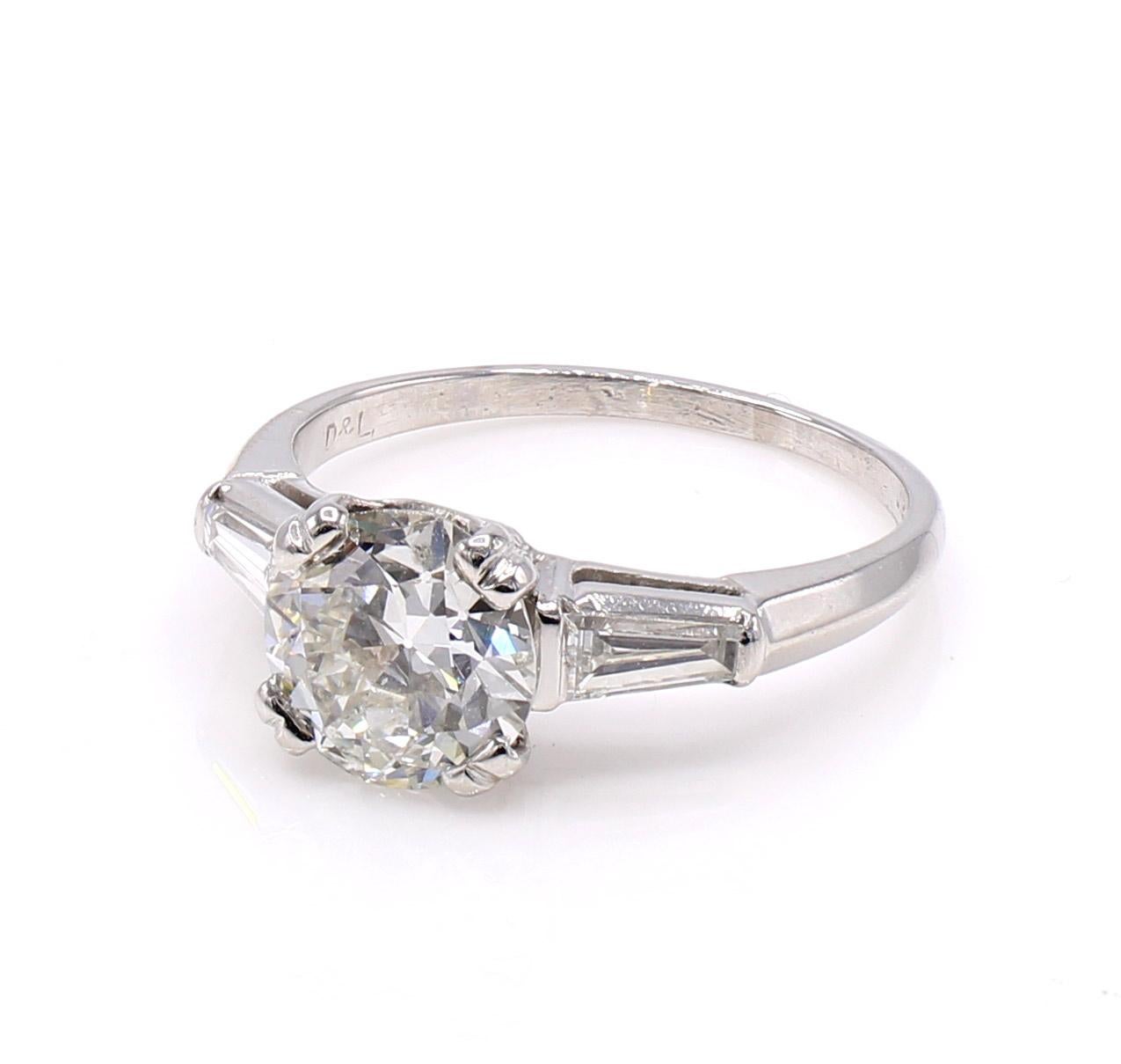 Beautifully cut lively and brilliant Old European Cut diamond set in a handcrafted platinum ring mount embellished by 2 bright white tapered baguettes on either side of the shank. The Old European Cut diamond weighing 1.62 carats has a wonderful