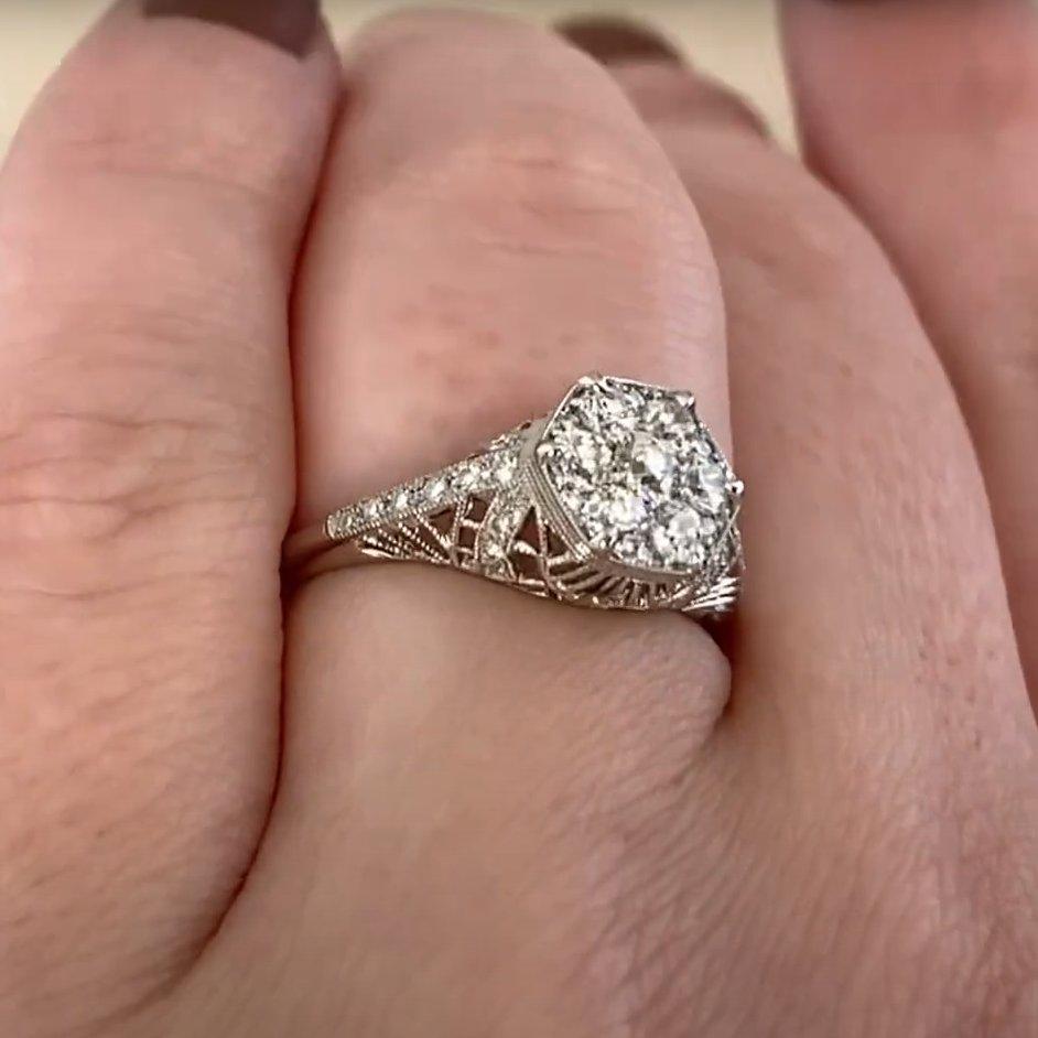 Este exquisito anillo exhibe un impresionante racimo central de diamantes de talla europea antigua con un peso combinado de aproximadamente 0,50 quilates. Los diamantes presentan un encantador color J y una claridad general de VS2 a SI1. El engaste