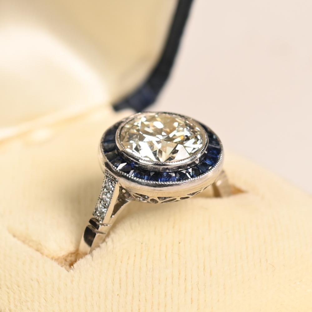 Questo squisito anello di fidanzamento con aureola e diamanti presenta al centro un diamante mozzafiato di circa 2,00 carati taglio vecchio europeo, che irradia un'eleganza senza tempo. Classificato di colore K e di purezza VS1, il diamante presenta