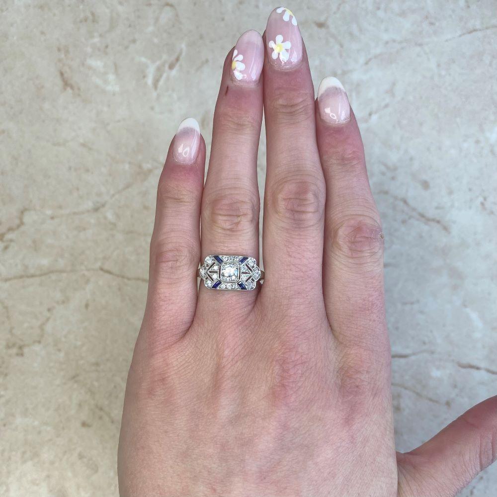 Cette exquise bague de style Art déco est un chef-d'œuvre intemporel, méticuleusement réalisé à la main dans un luxueux platine. En son centre brille un diamant de taille européenne ancienne, pesant environ 0,25 carats, d'une couleur J et d'une